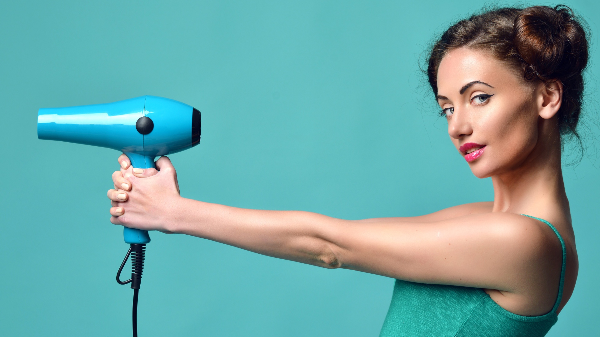 Красивая девушка с феном в руках на голубом фоне