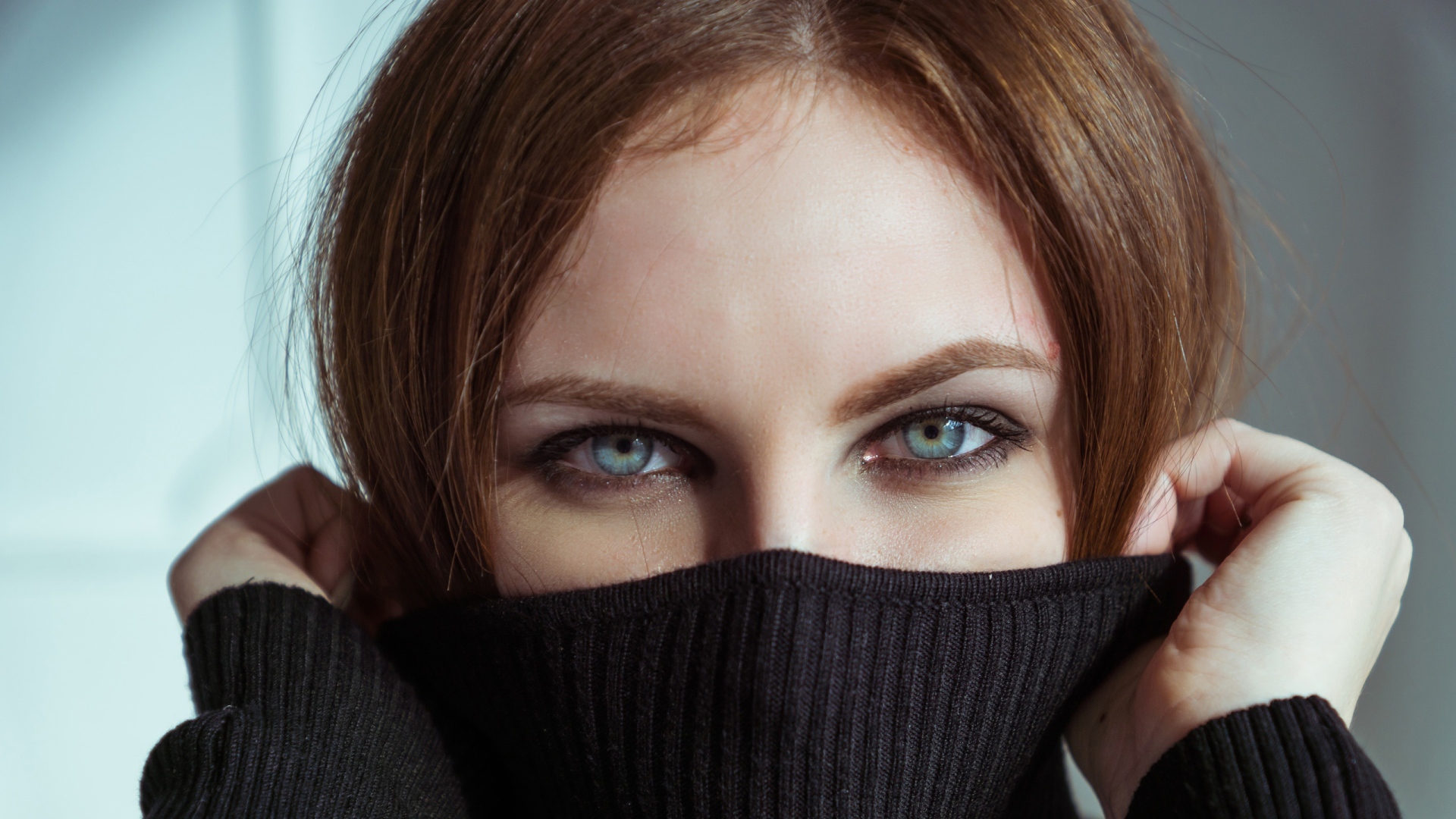 Красивая девушка с голубыми глазами закрыла лицо свитером 