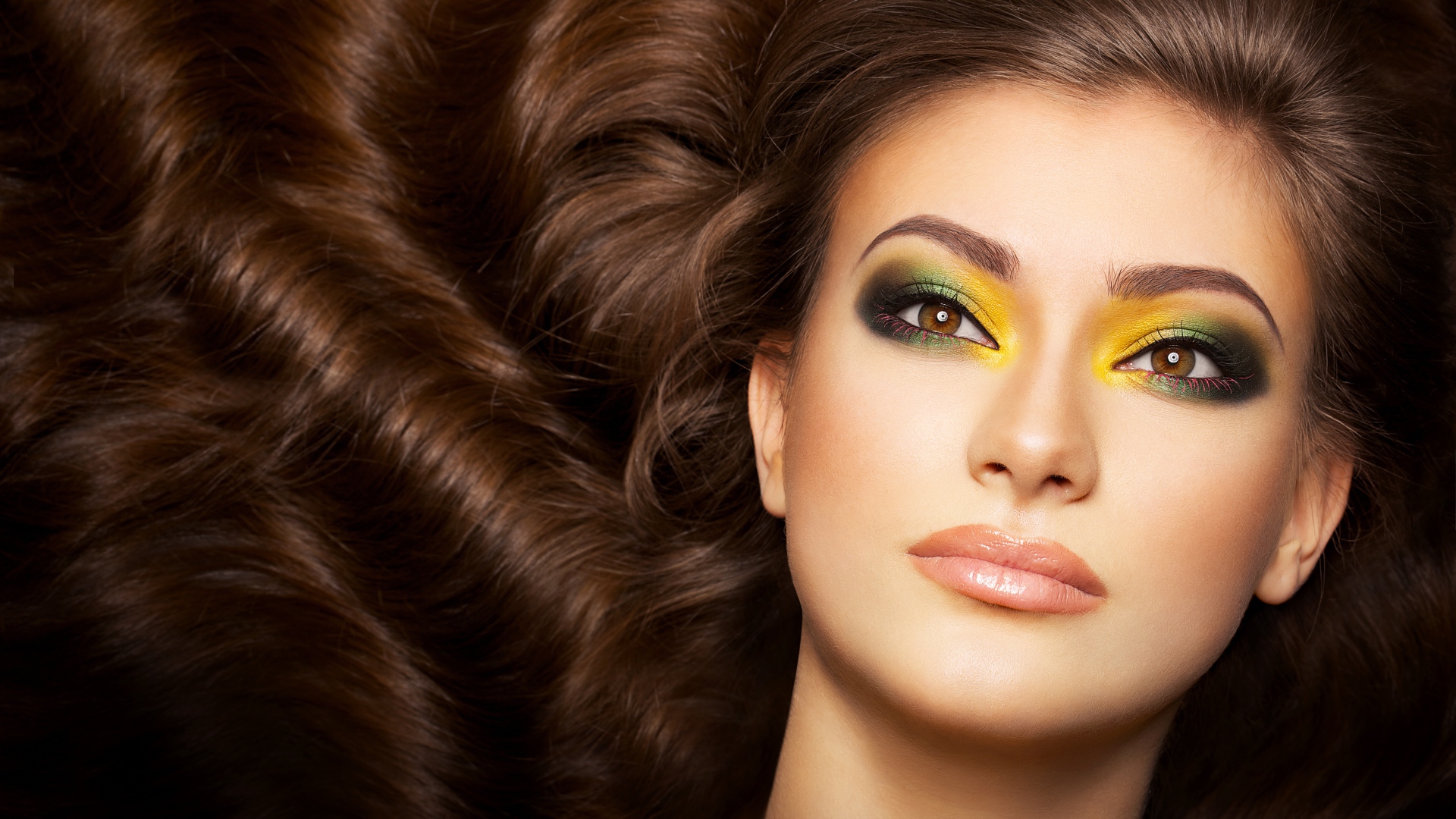 Красивая длинноволосая девушка с ярким макияжем на глазах 