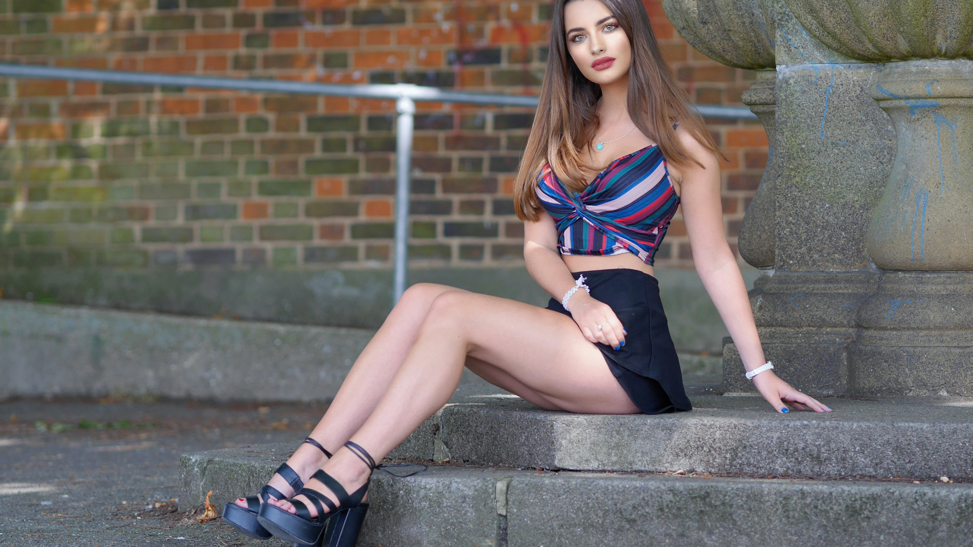 Beautiful long-legged girl in a short skirt sits on the steps