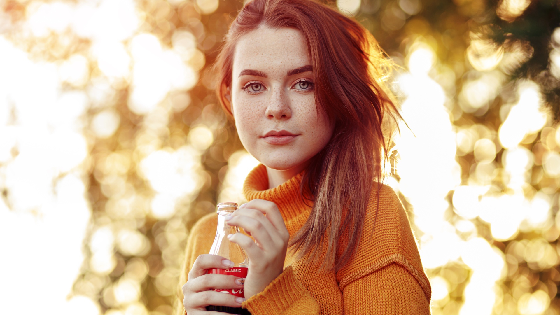 Красивая рыжеволосая девушка с бутылкой кока колы в руке 