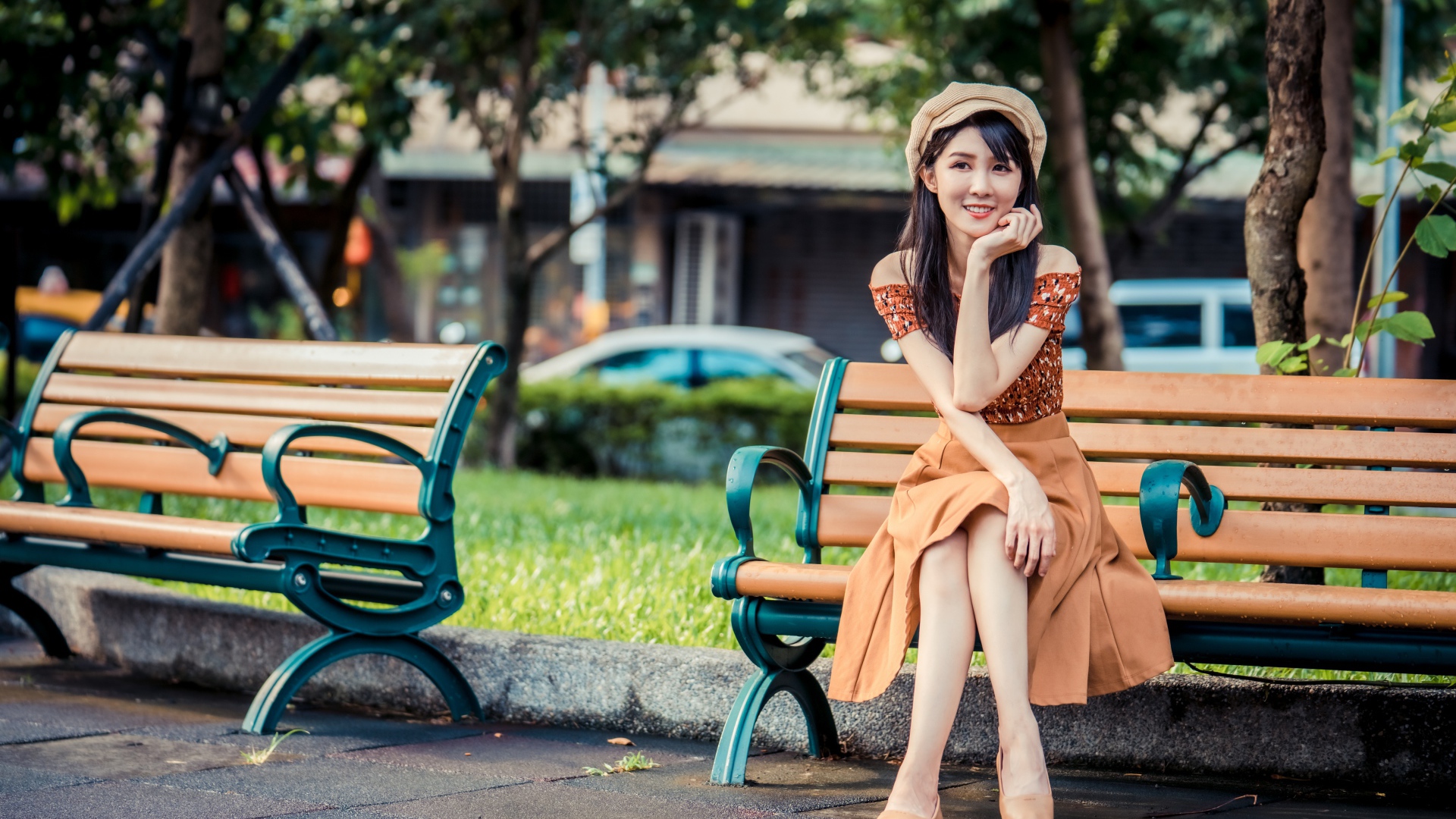 Красивая улыбающаяся азиатка сидит на лавке в парке