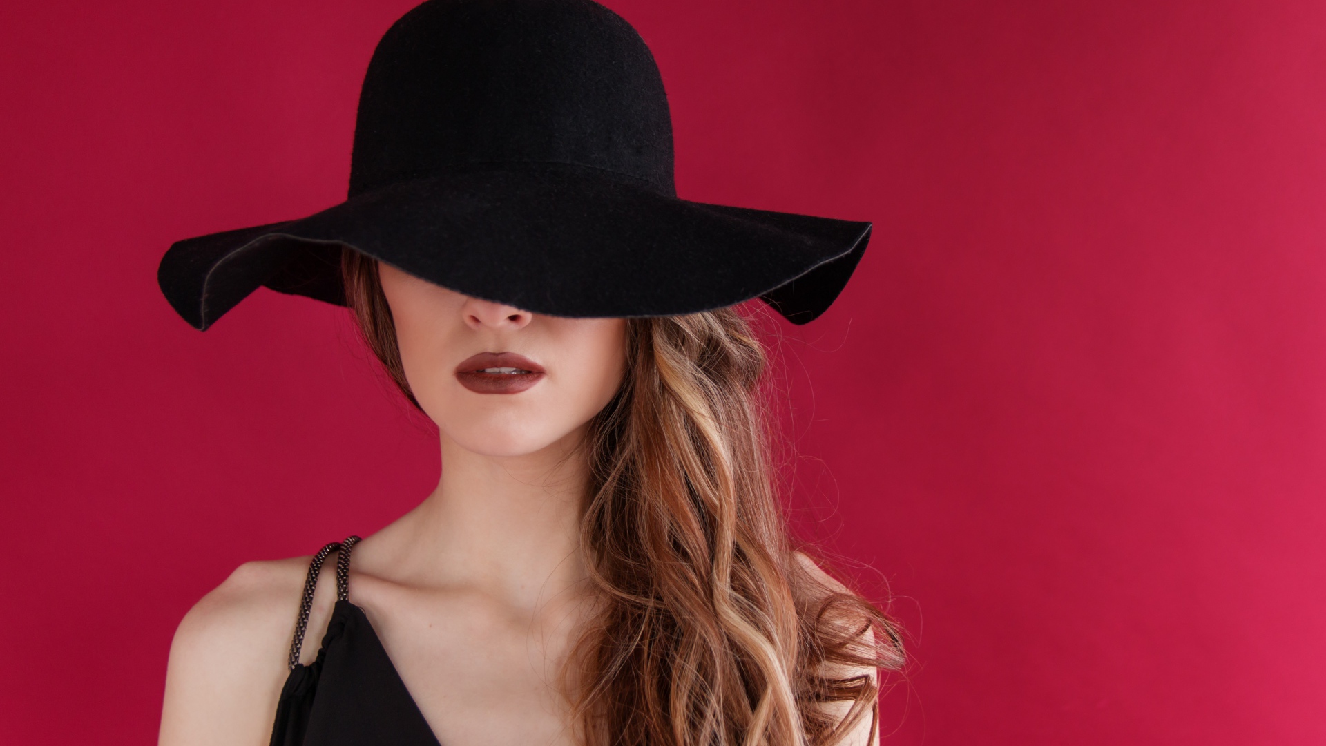 Большая черная шляпа закрывает лицо девушки