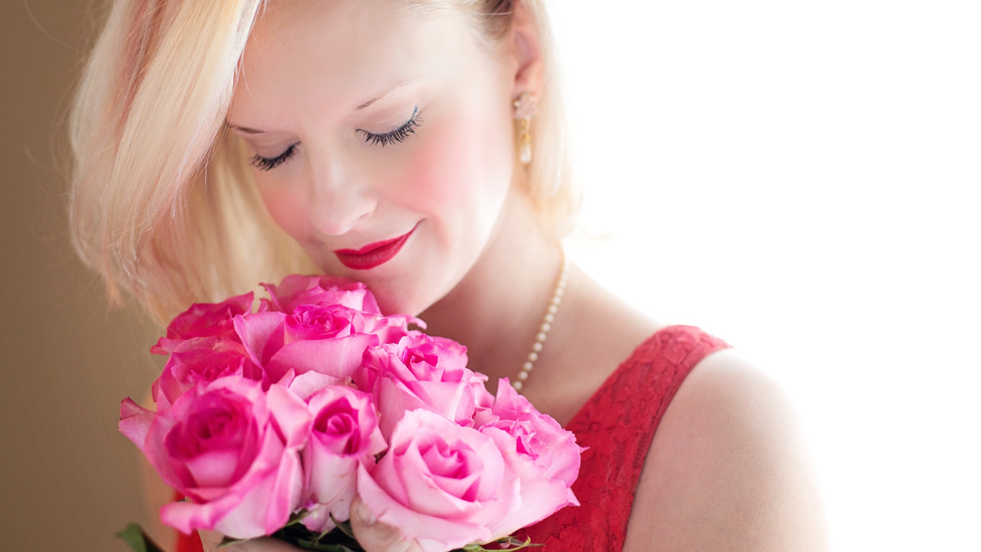 Блондинка с закрытыми глазами нюхает букет роз