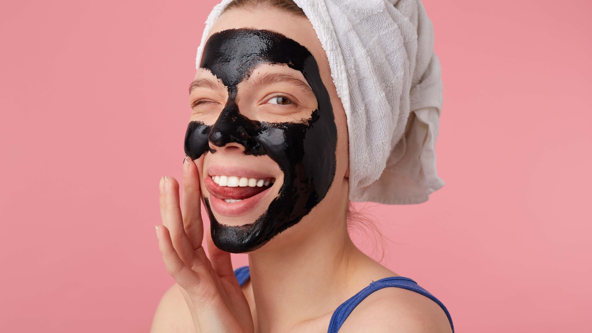 Смешная молодая девушка с черной косметической маской на лице 