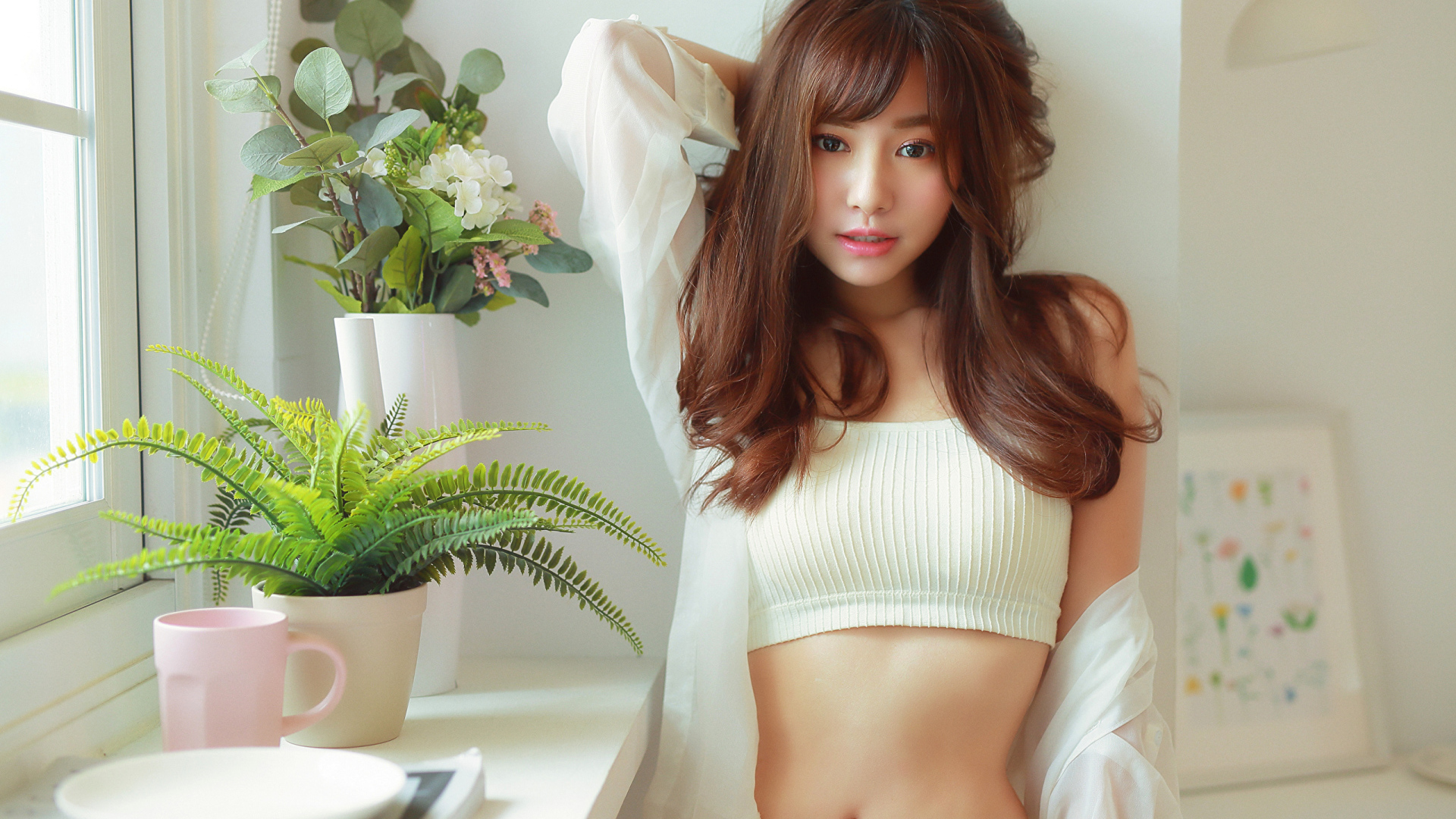 Нежная девушка азиатка стоит у окна