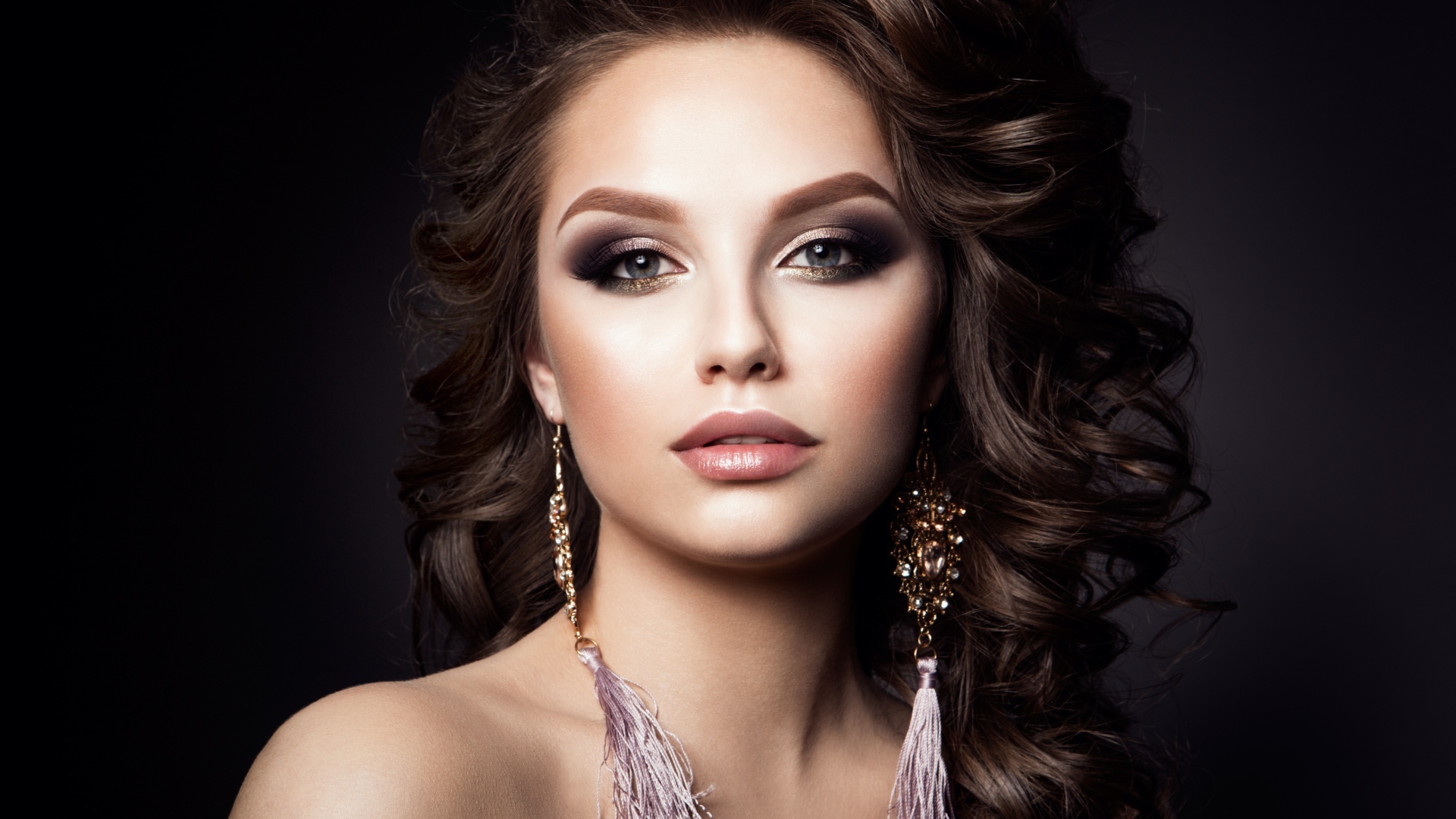 Девушка с прической с красивыми сережками на сером фоне 