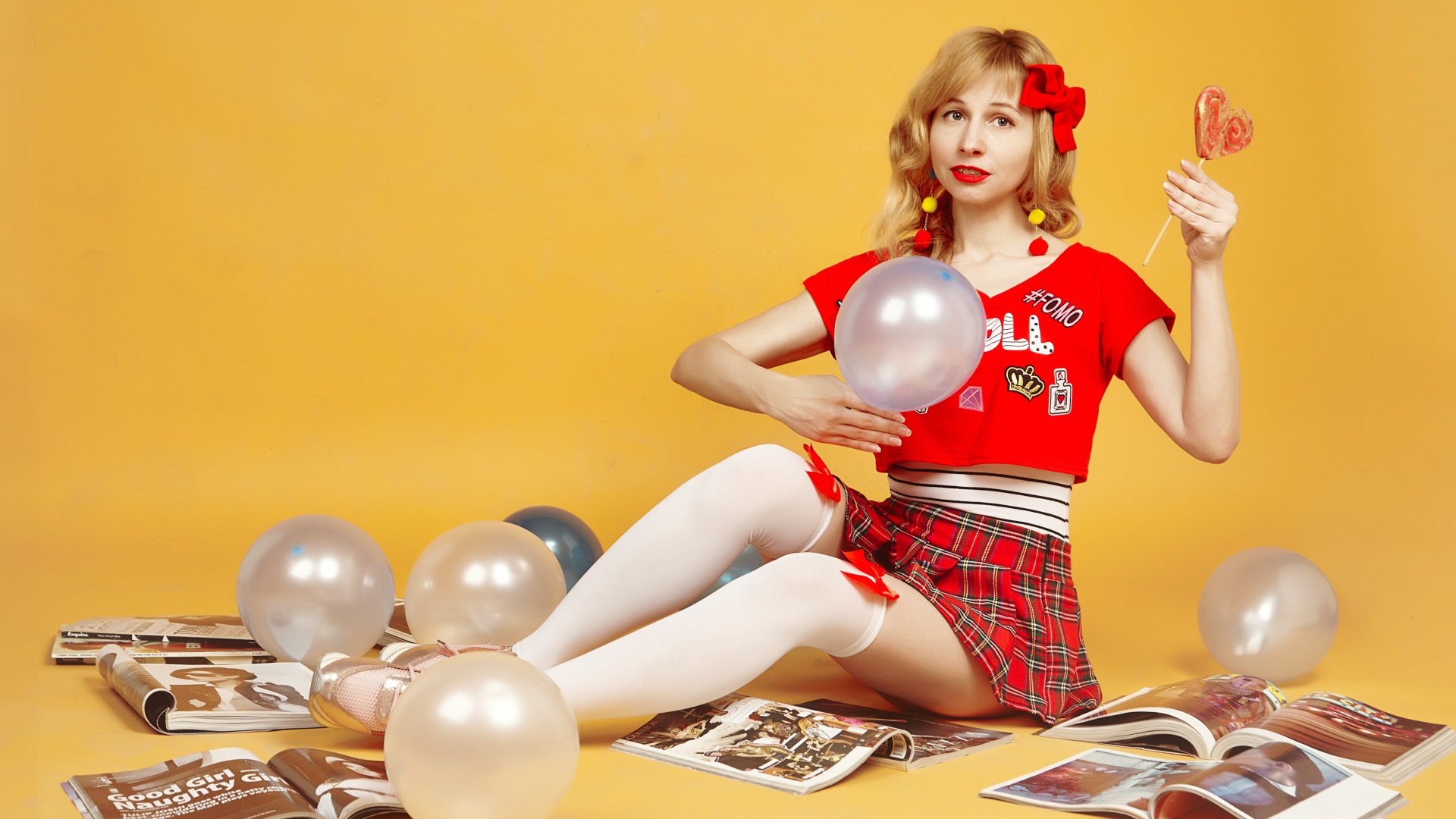 Девушка с шариками и журналами сидит на полу