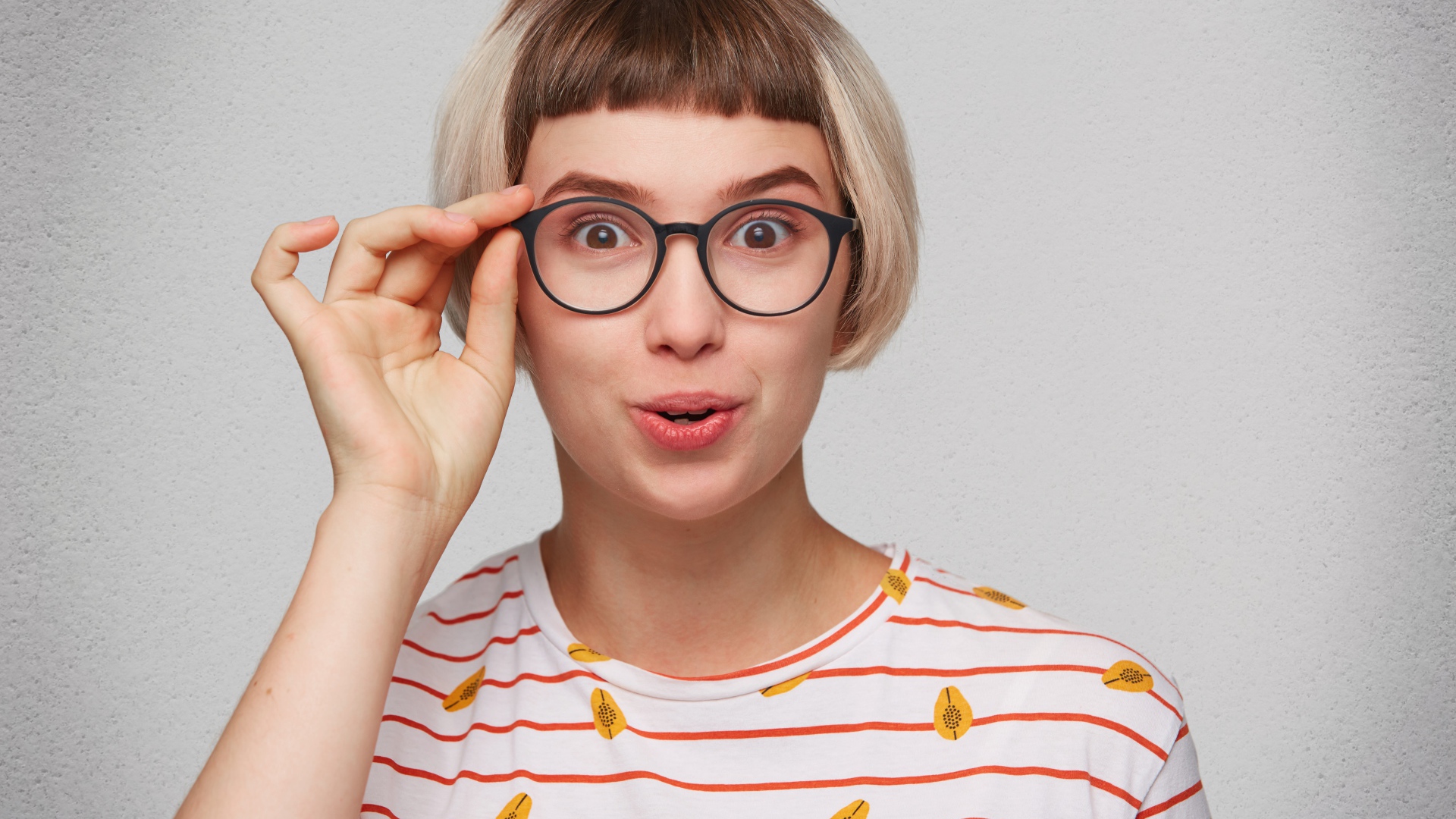 Девушка с короткой стрижкой поправляет очки 