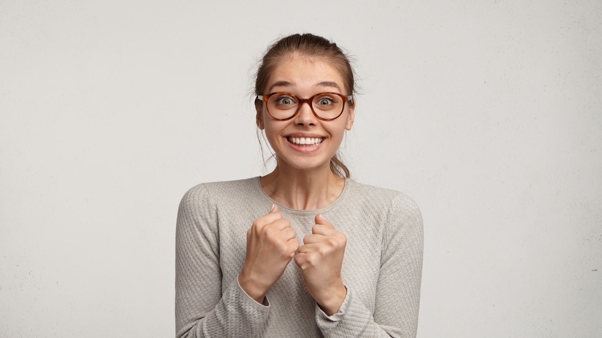 Радостная девушка в очках для зрения на сером фоне 