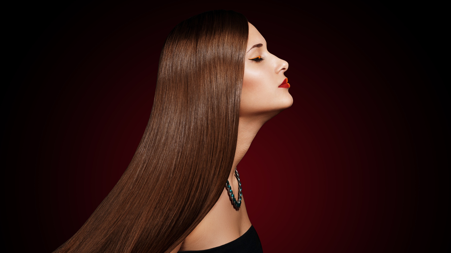 Длинноволосая шатенка с закрытыми глазами на красном фоне