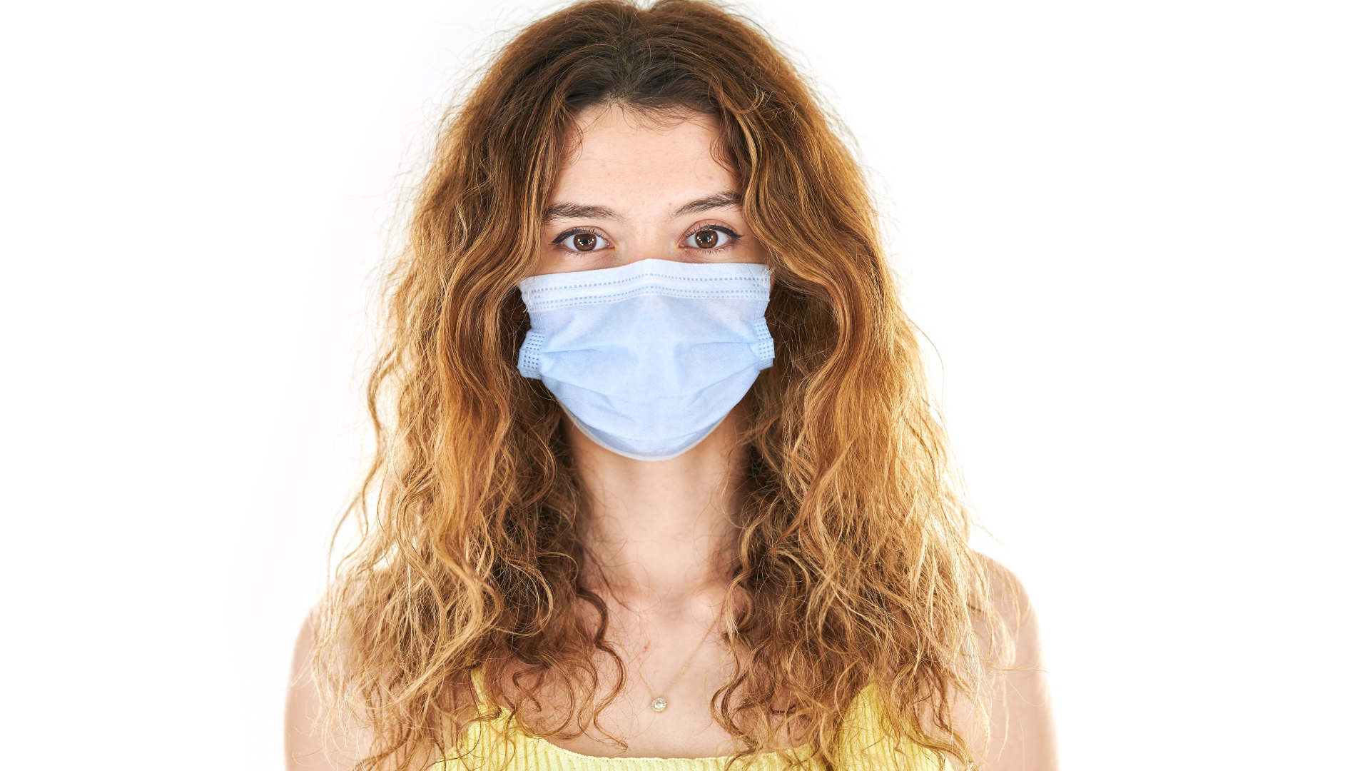 Длинноволосая девушка в маске от коронавируса на белом фоне