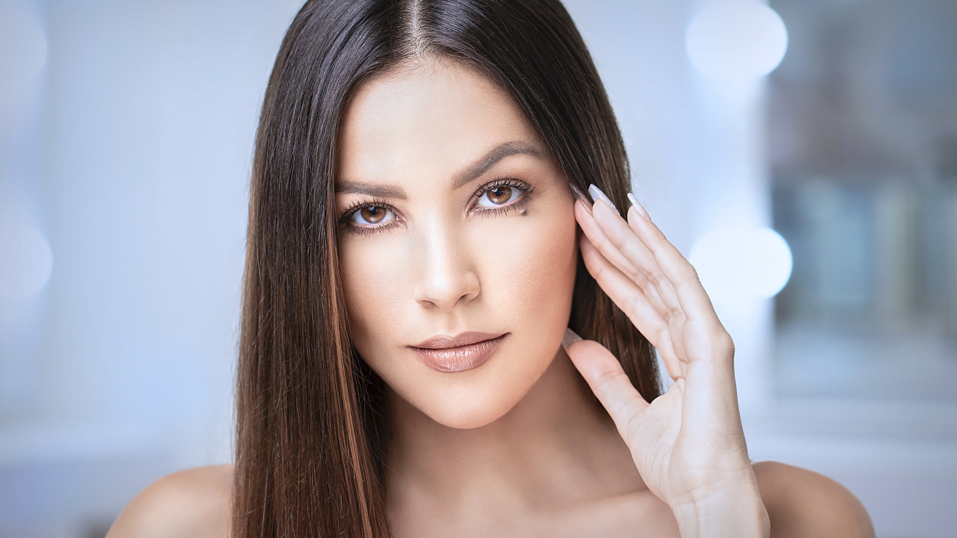 Стильная кареглазая длинноволосая брюнетка с рукой у лица