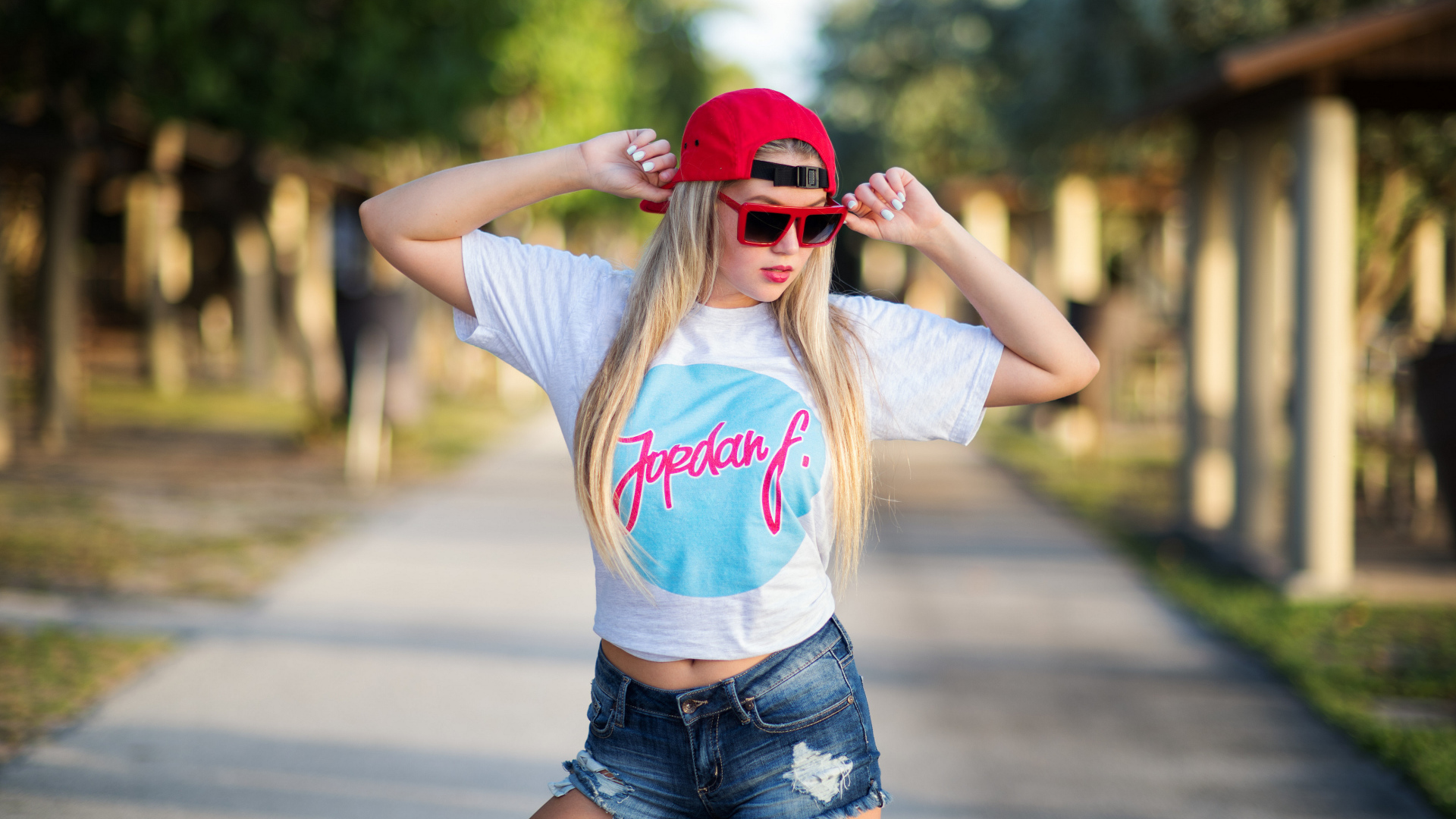 Стильная девушка в красной кепке и джинсовых шортах 