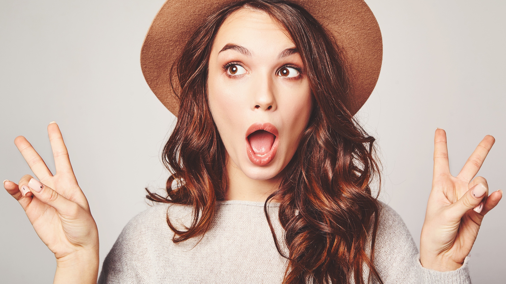 Удивленная девушка с длинными волосами в коричневой шляпе 