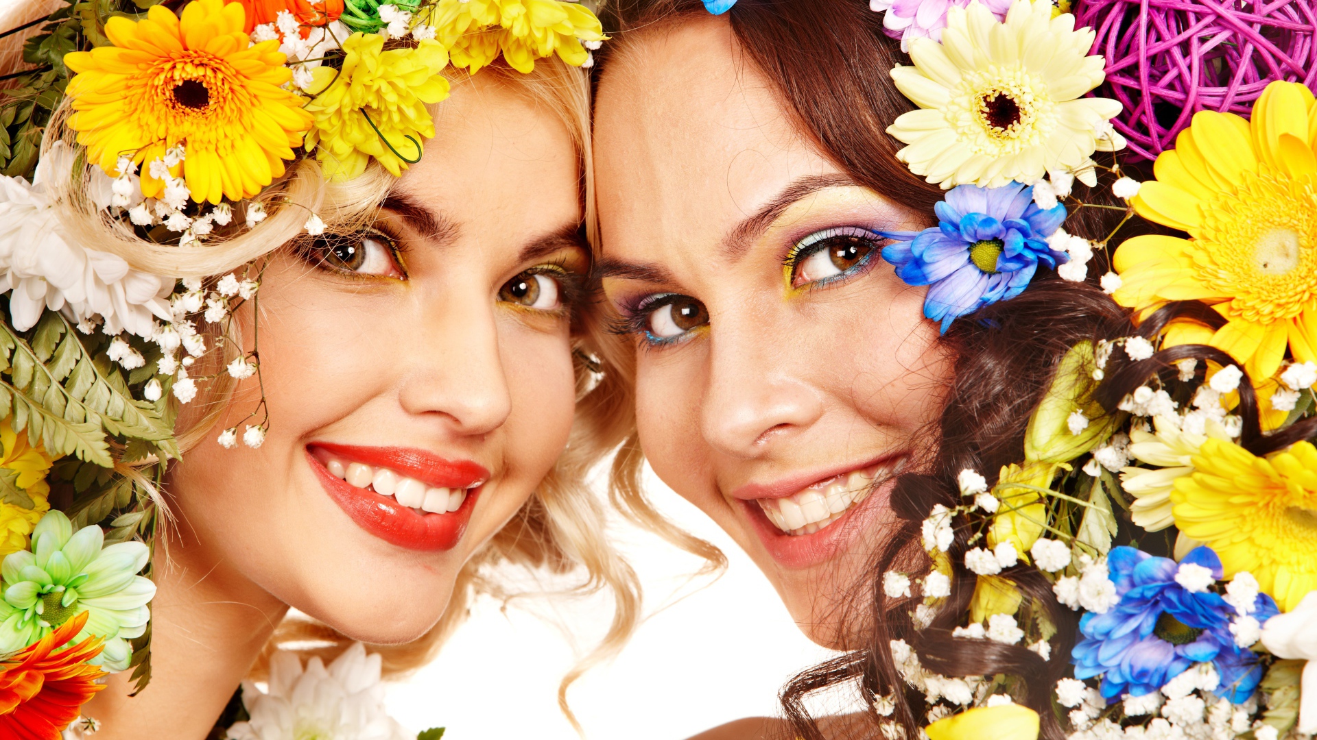 Две яркие улыбающиеся девушки с цветами в волосах 