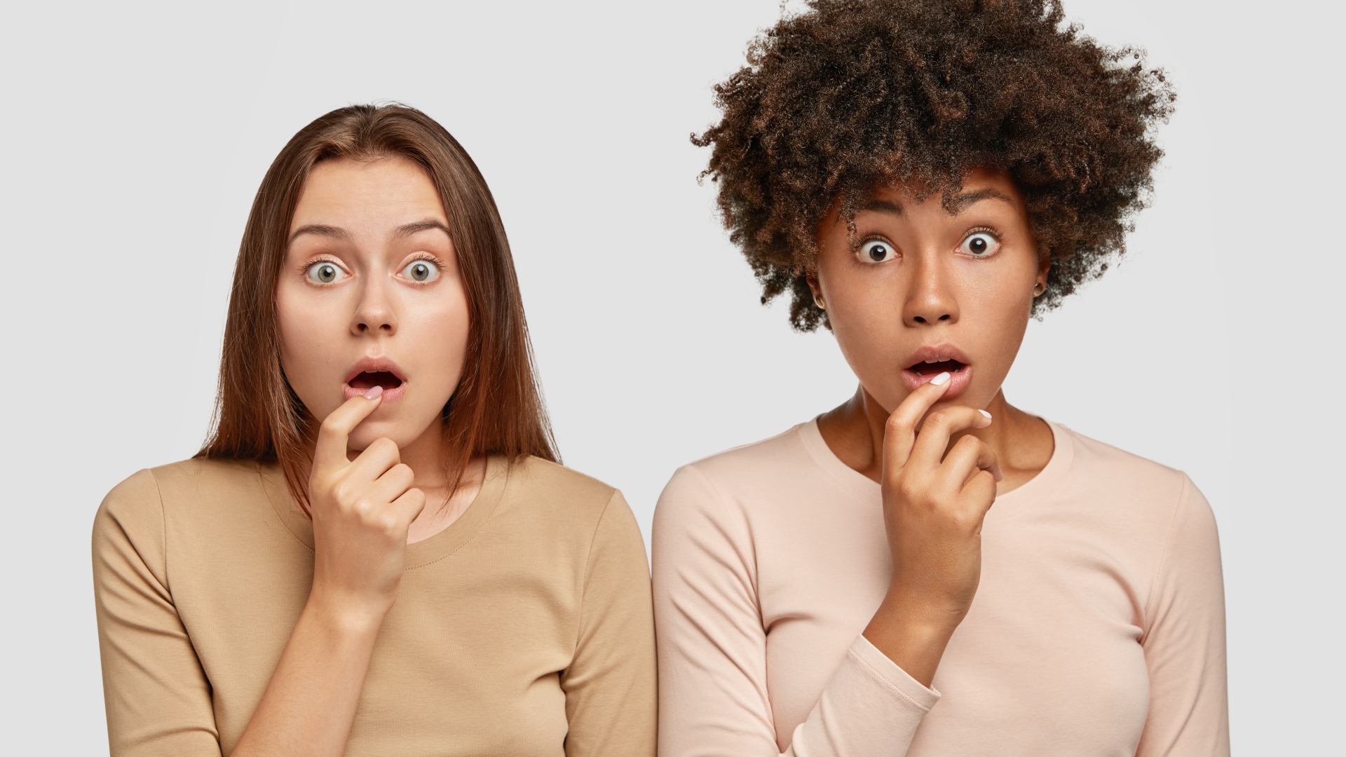 Две удивленные девушки на сером фоне 