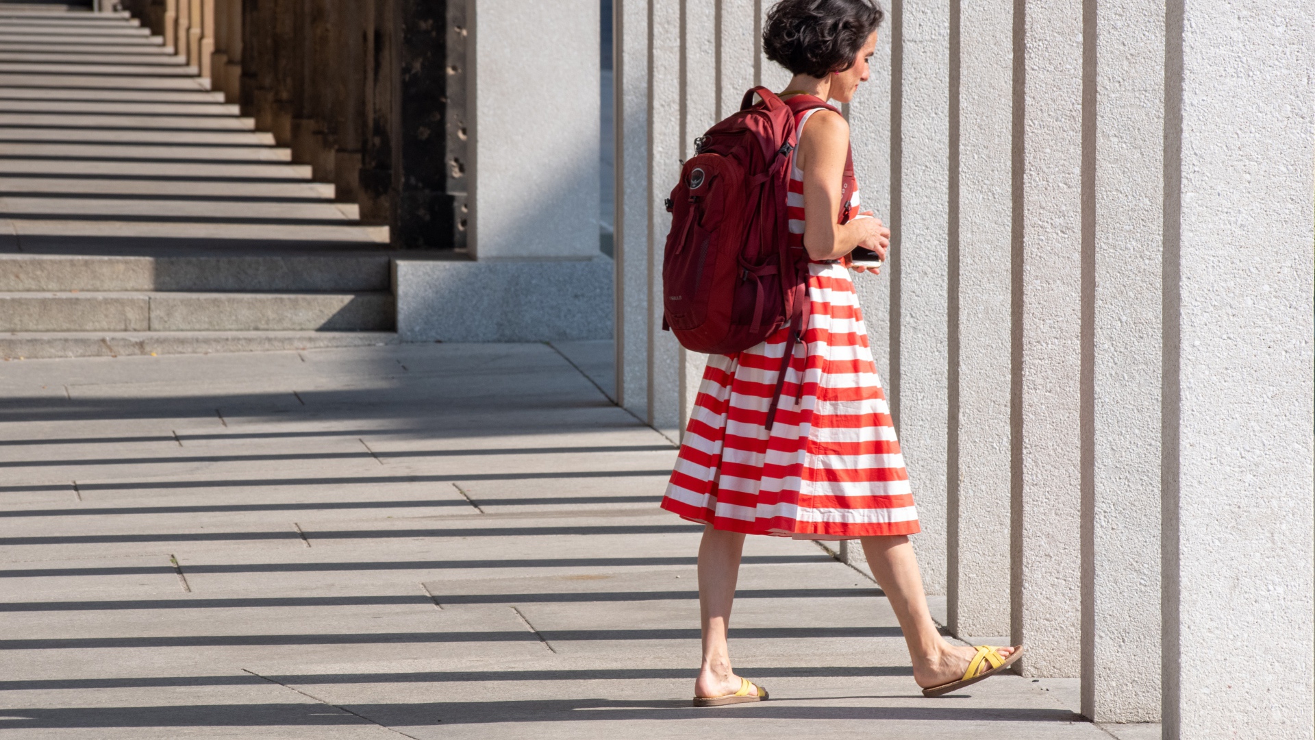 Женщина в красном полосатом платье с рюкзаком