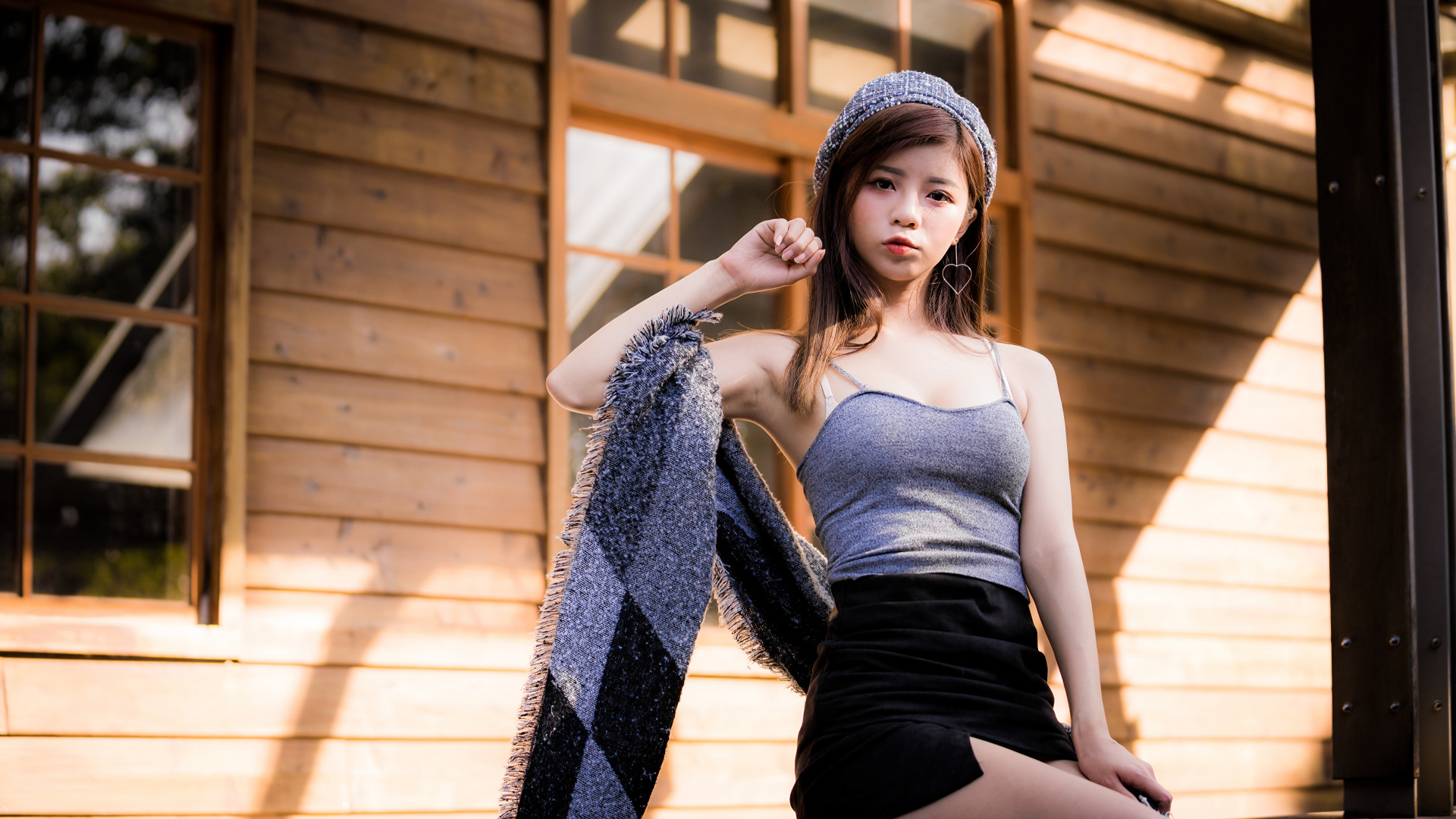 Молодая девушка азиатка в короткой юбке сидит на подоконнике 