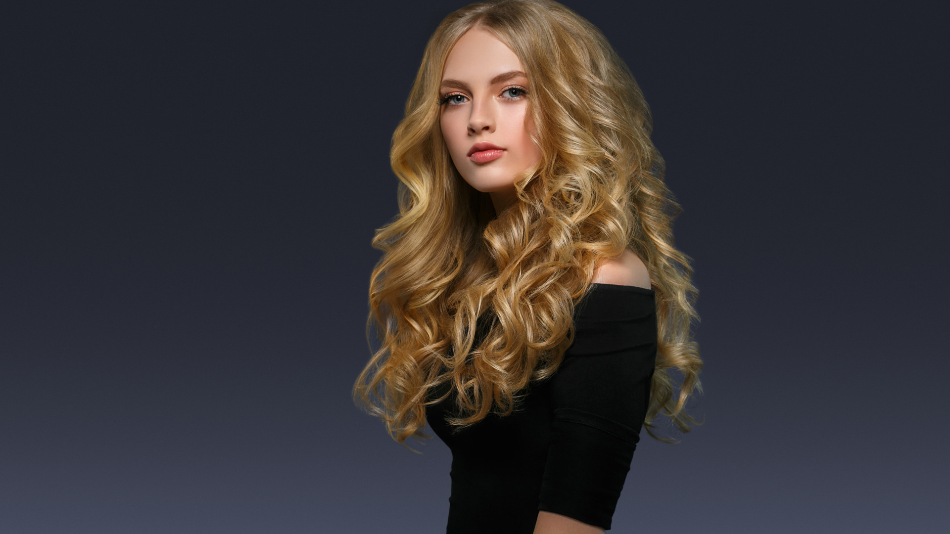 Молодая блондинка с красивыми длинными волосами в черном платье