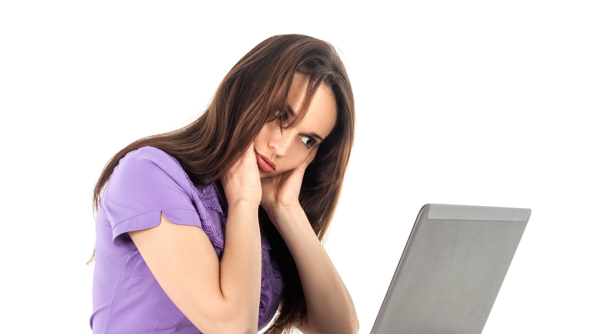 Молодая девушка сидит за ноутбуком на белом фоне