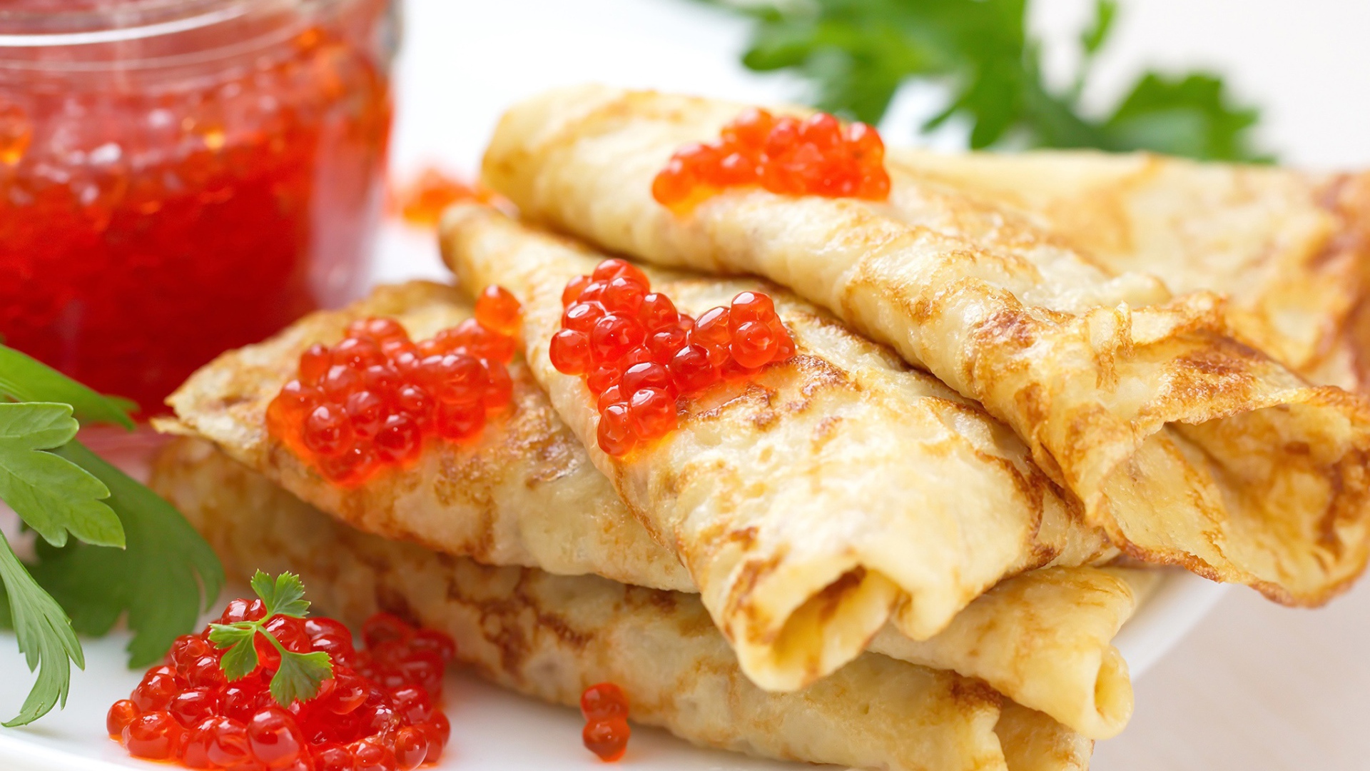 Аппетитные тонкие блины с красной икрой на тарелке с петрушкой угощение на Масленицу