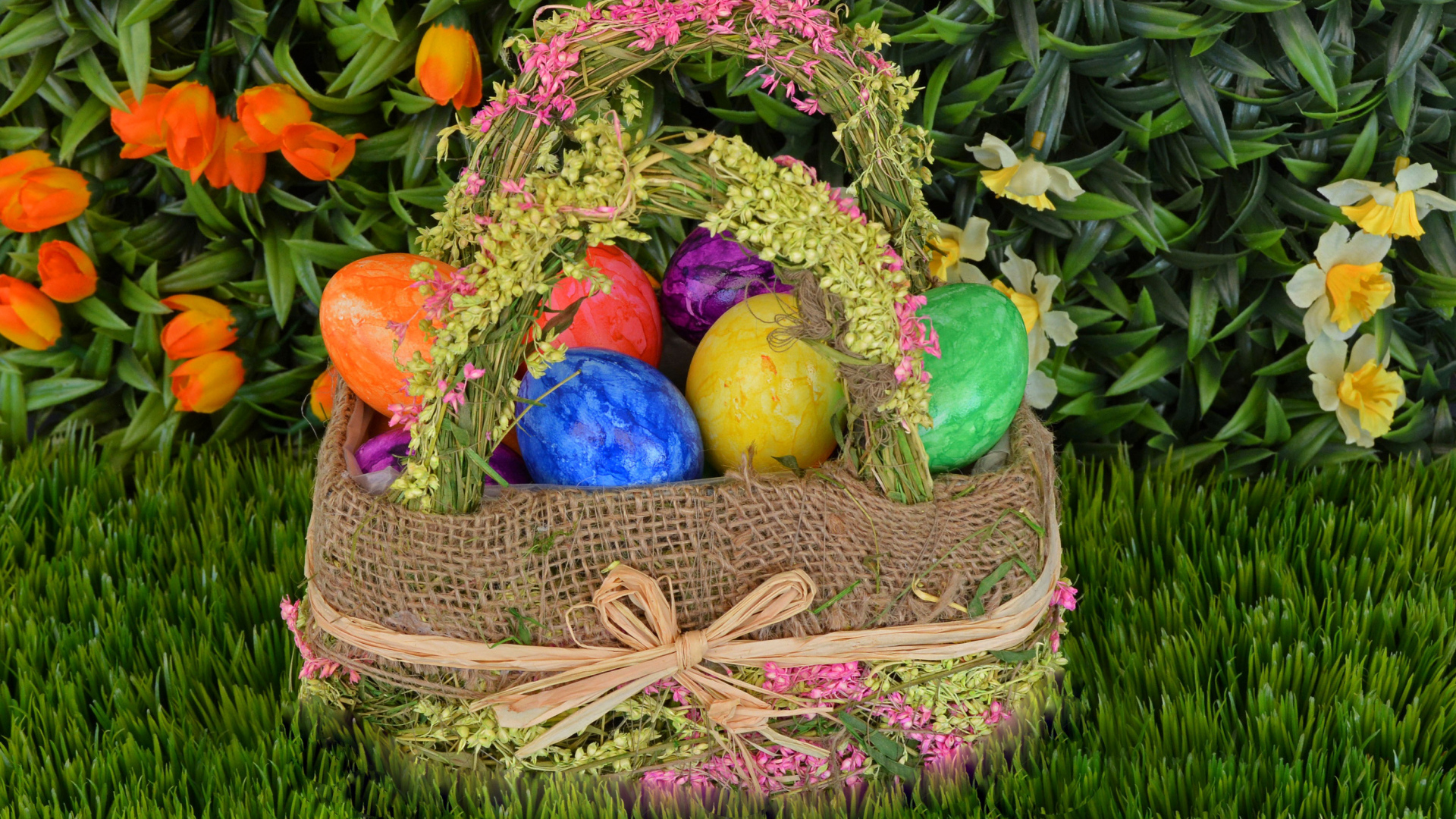 Разноцветные пасхальные яйца в корзине на зеленой траве на праздник 