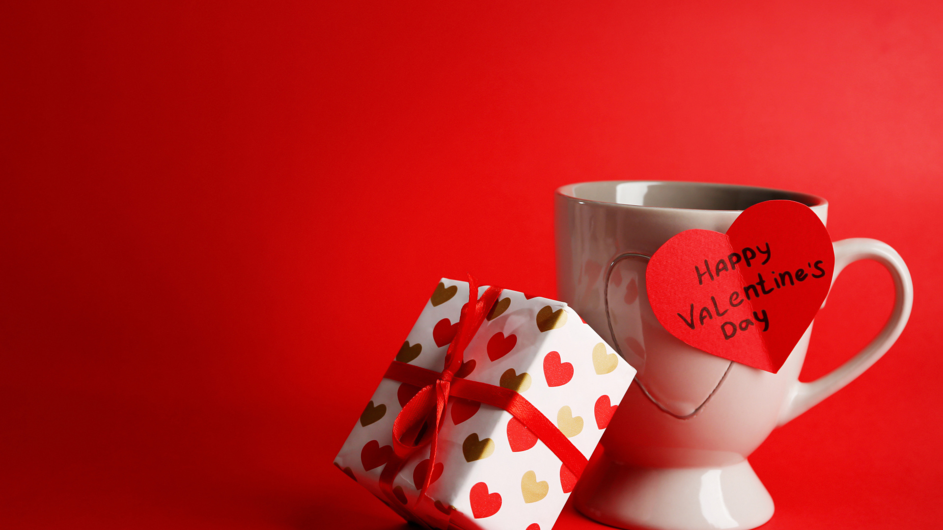 Кружка, сердечко и подарок на красном фоне на День Святого Валентина 