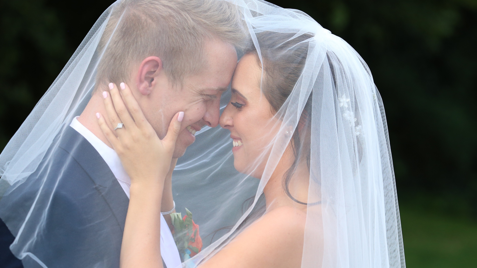 Жених и невеста стоят под белой фатой