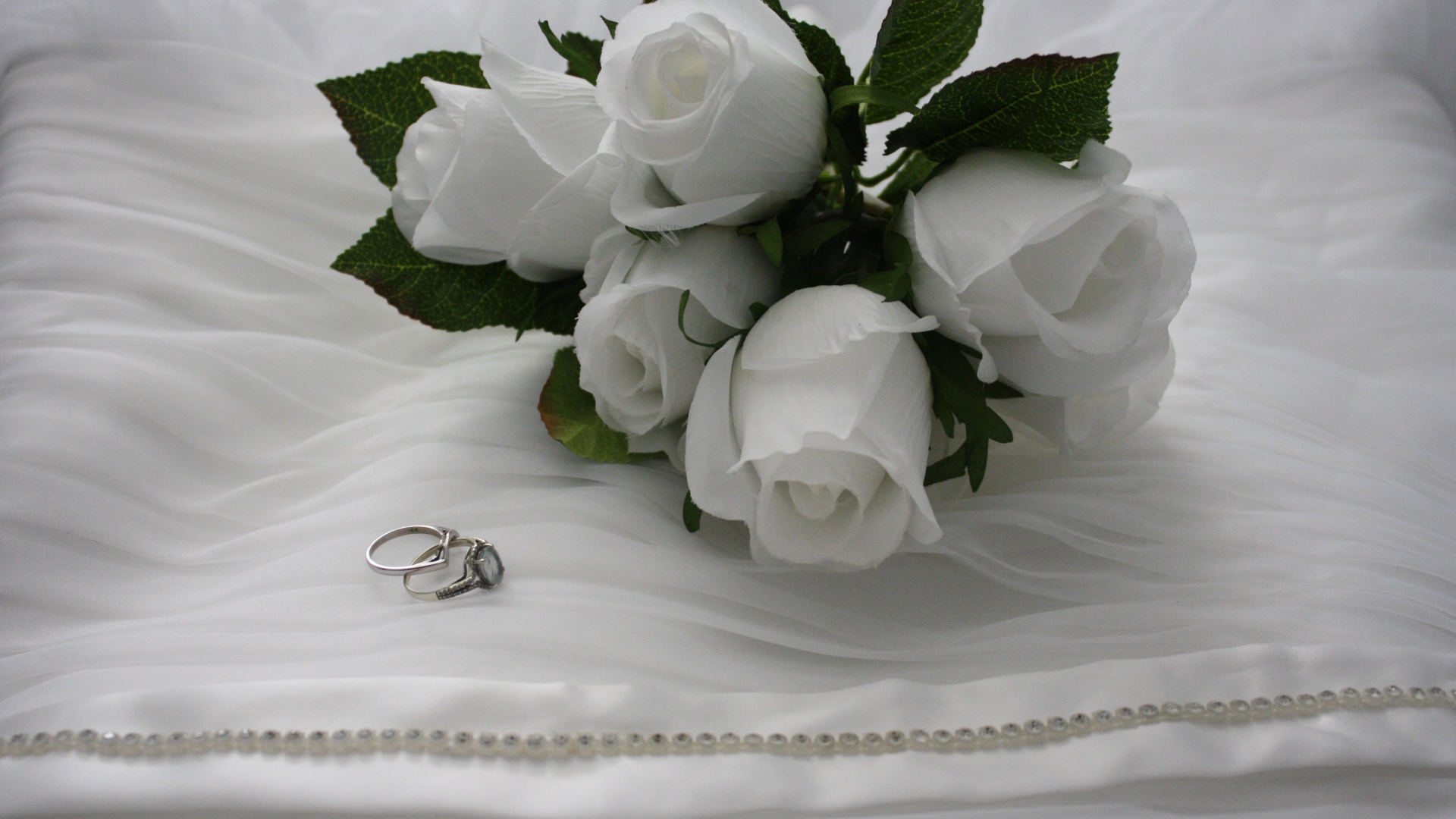 Белые бутоньерки с кольцами на белом покрывале 