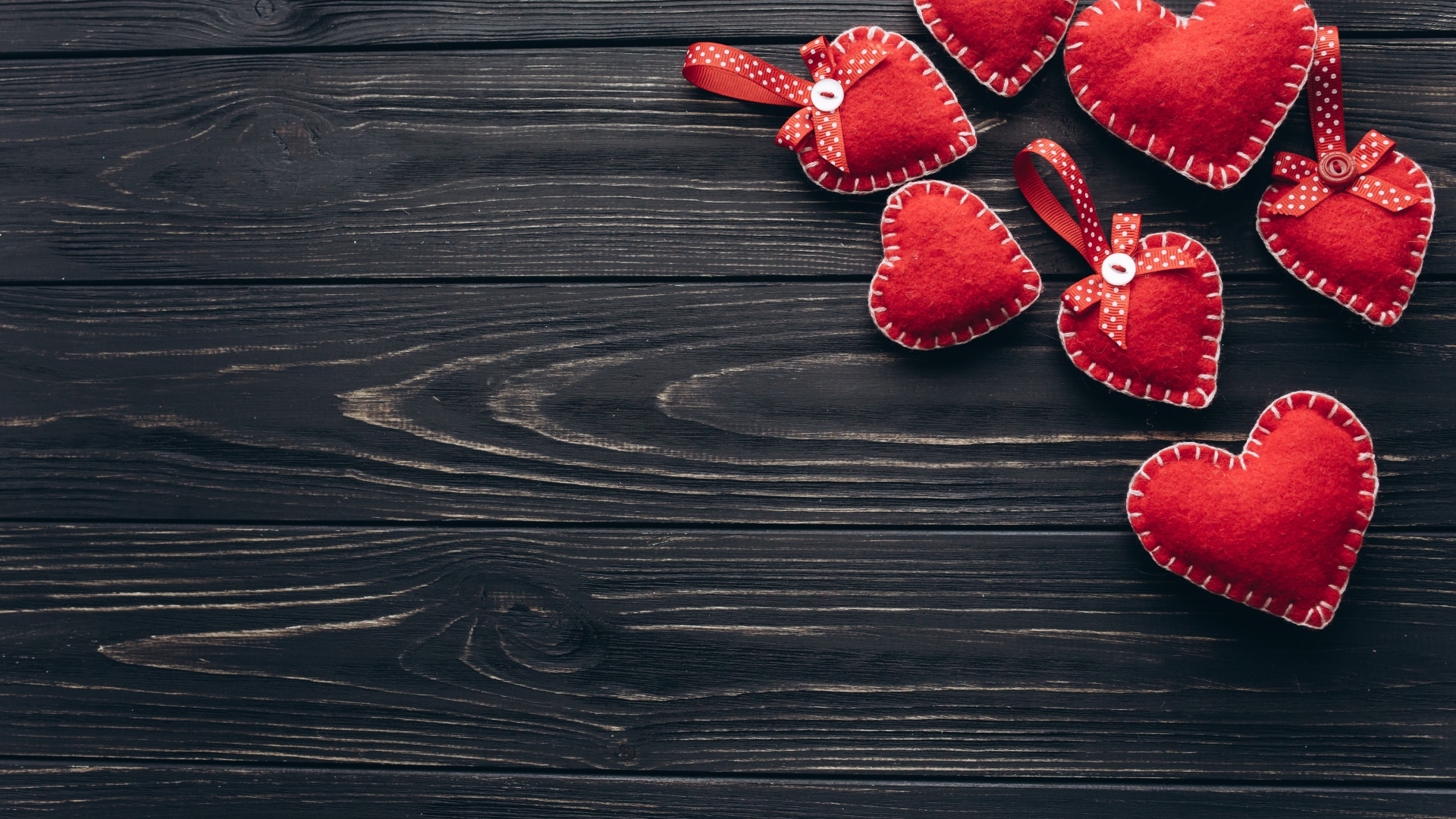 Много красных сердечек из фетра на деревянном столе
