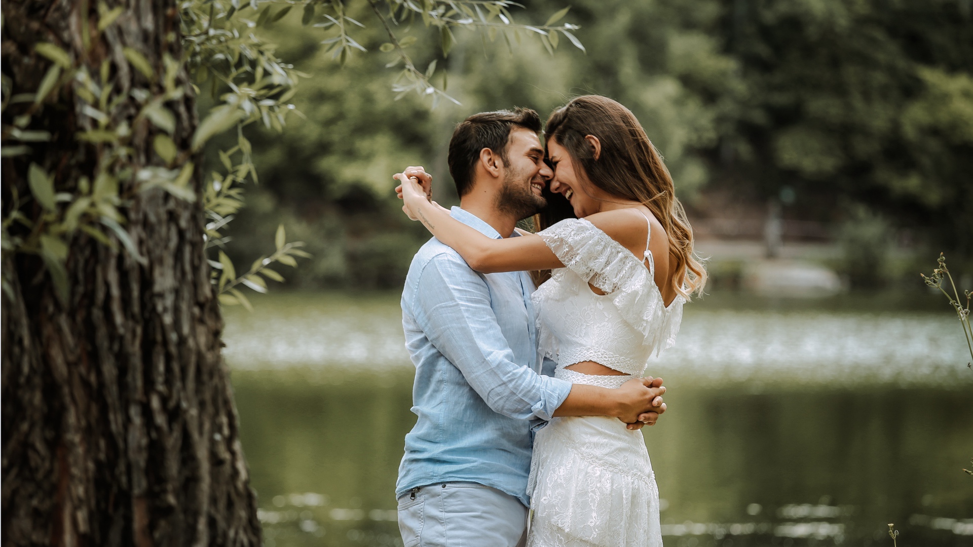 Влюбленная пара стоит у пруда в парке 