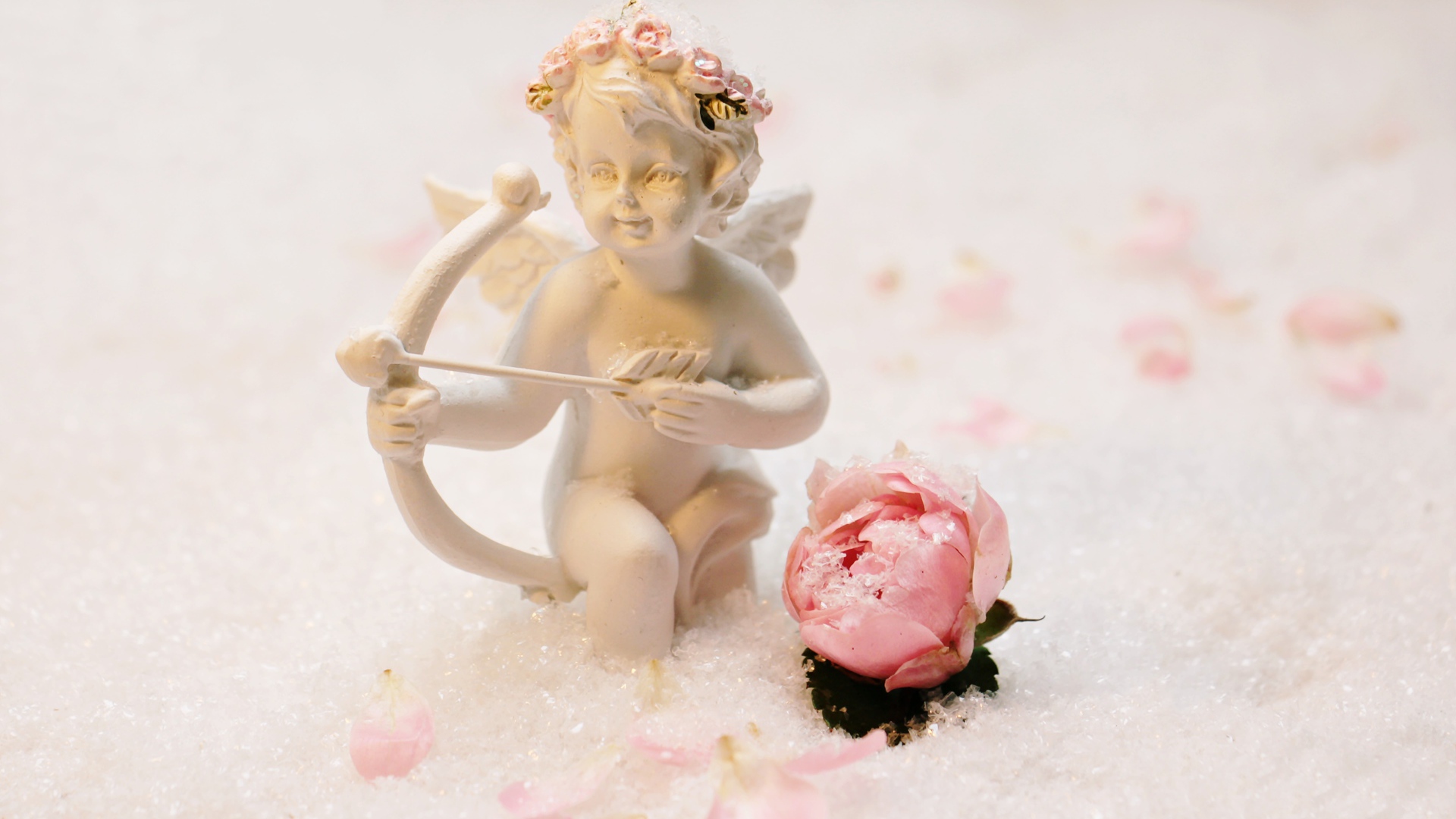 Статуэтка купидона с розой на снегу