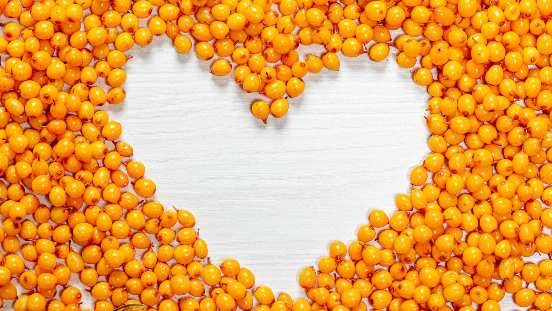 Сердце из ягод облепихи на столе 