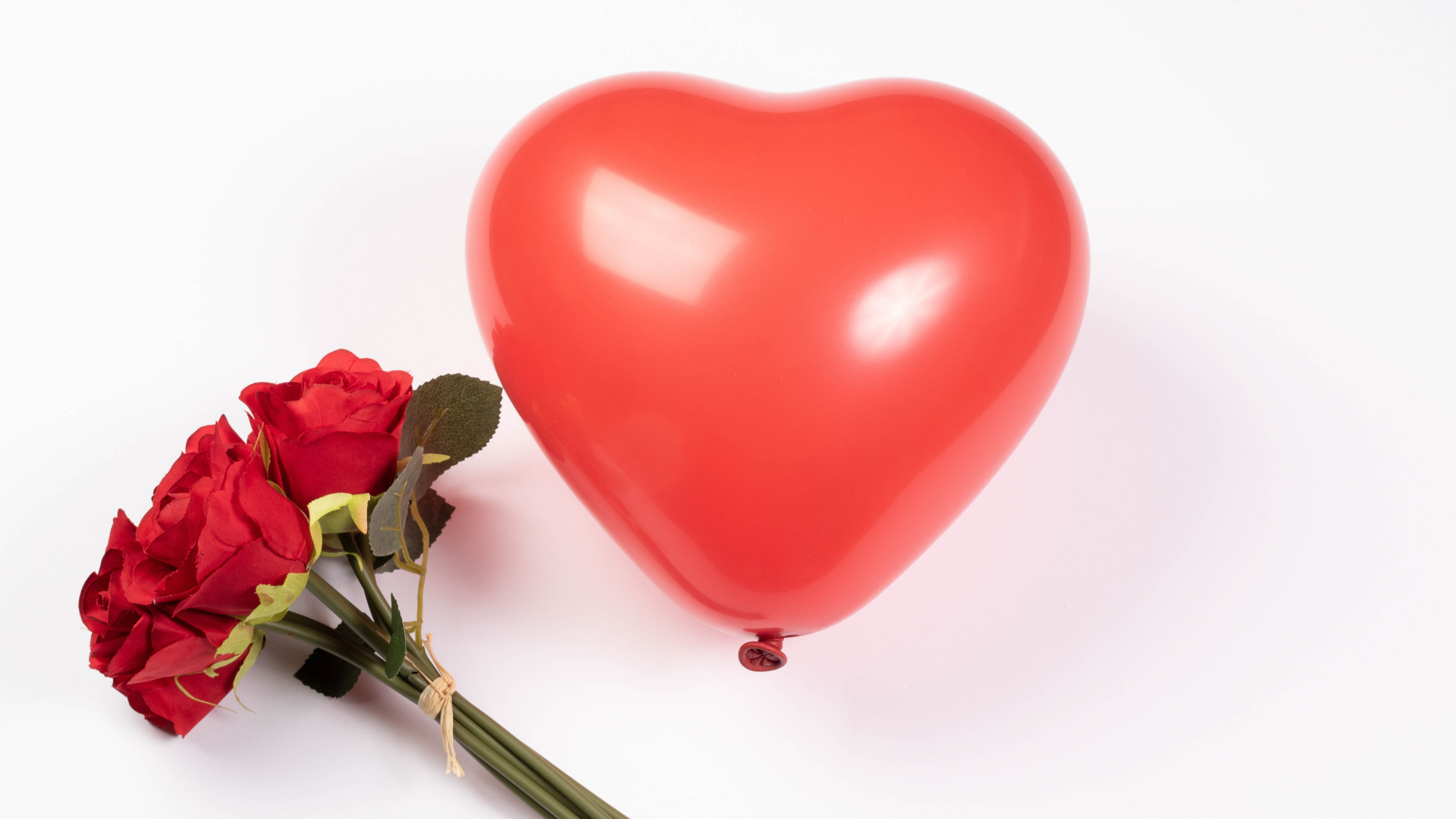Красный шарик в форме сердца с букетом роз на белом фоне