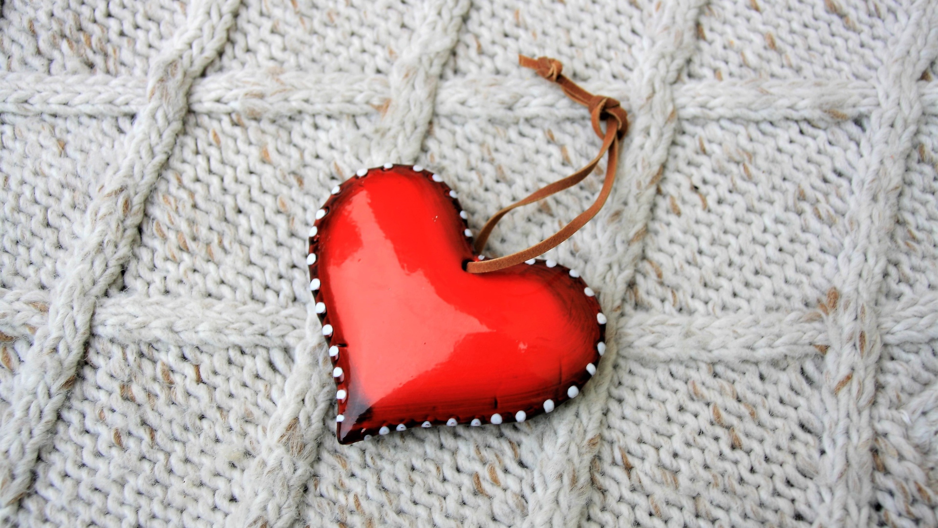 Красное сердце лежит на вязаном свитере 