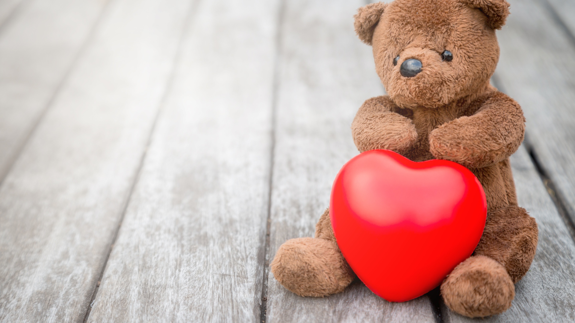 Медвежонок Тедди с красным сердцем сидит на столе