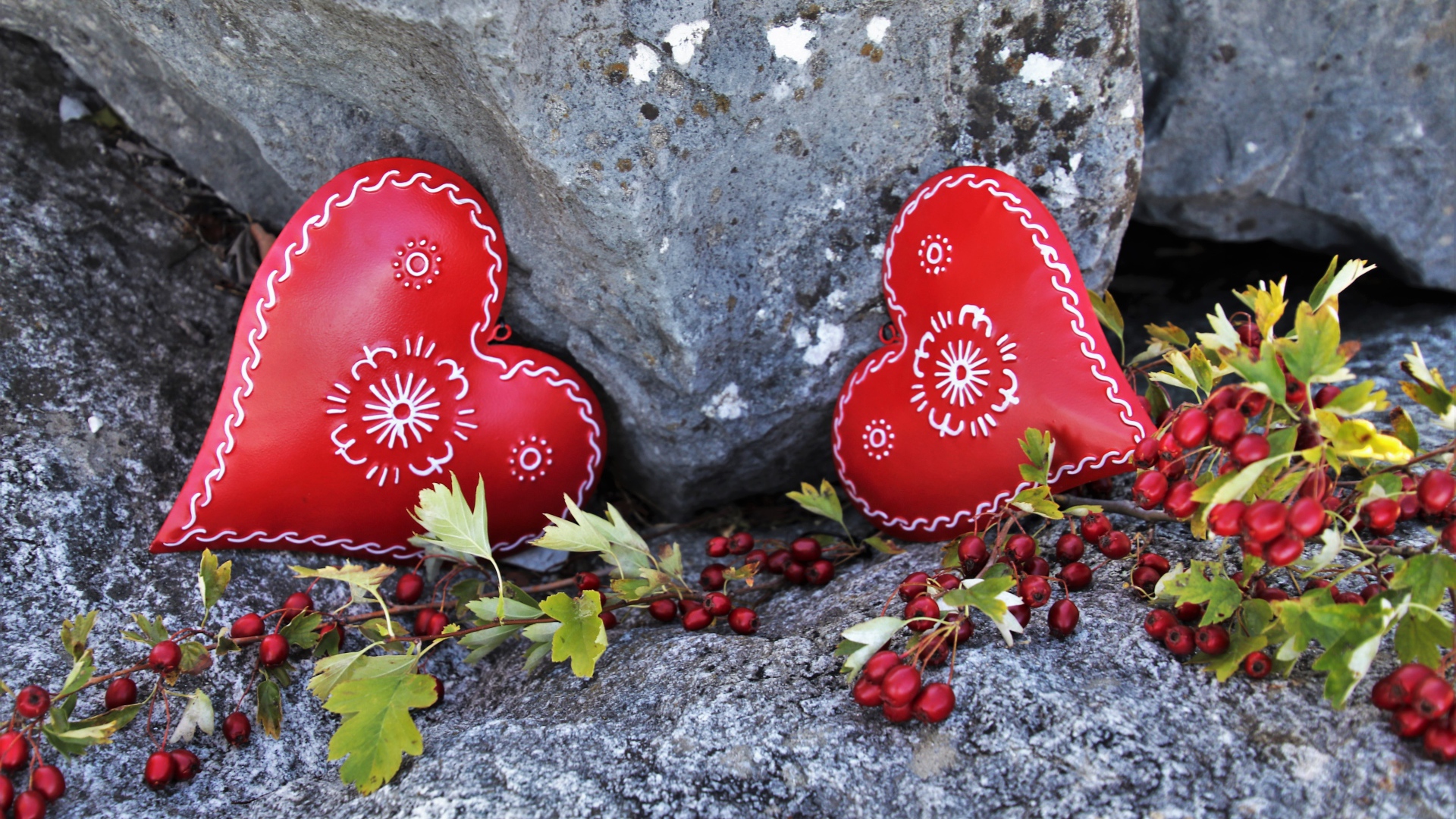 Два сердца лежат у камня с красными ягодами