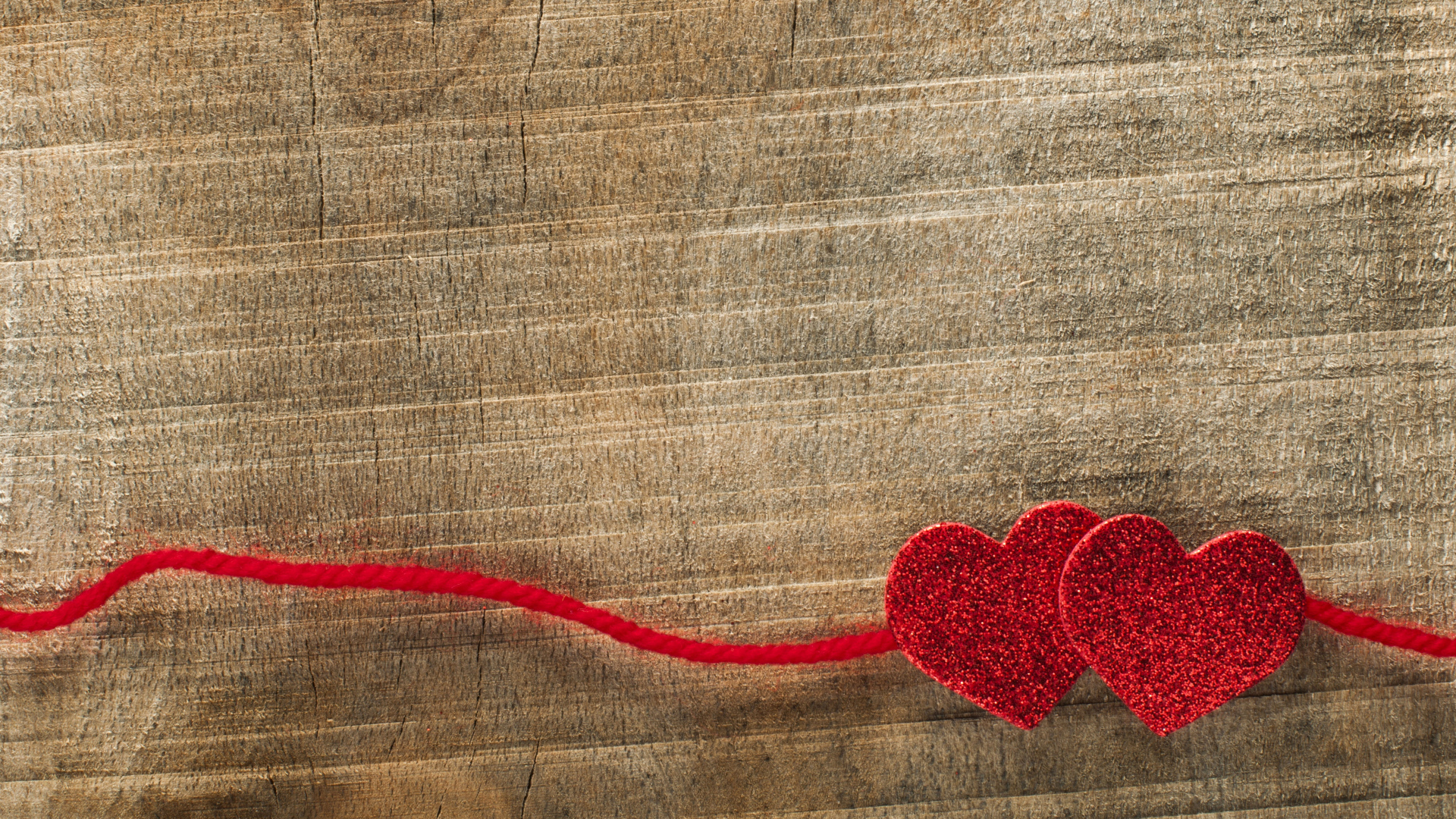 Два красных сердца со шнурком на деревянном фоне