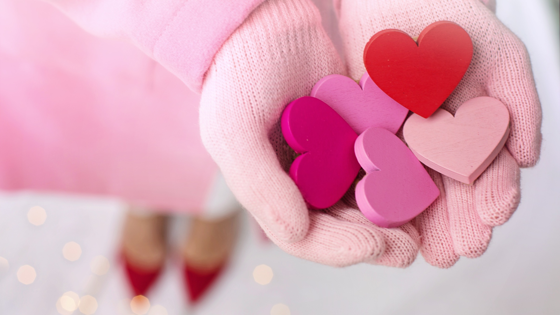 Деревянные сердечки в руках девушки в розовых перчатках 