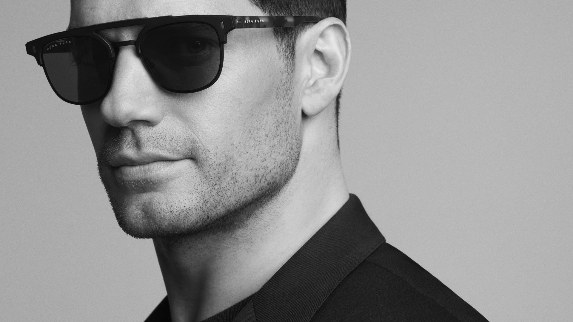 Актер Генри Кавилл в черных очках на сером фоне