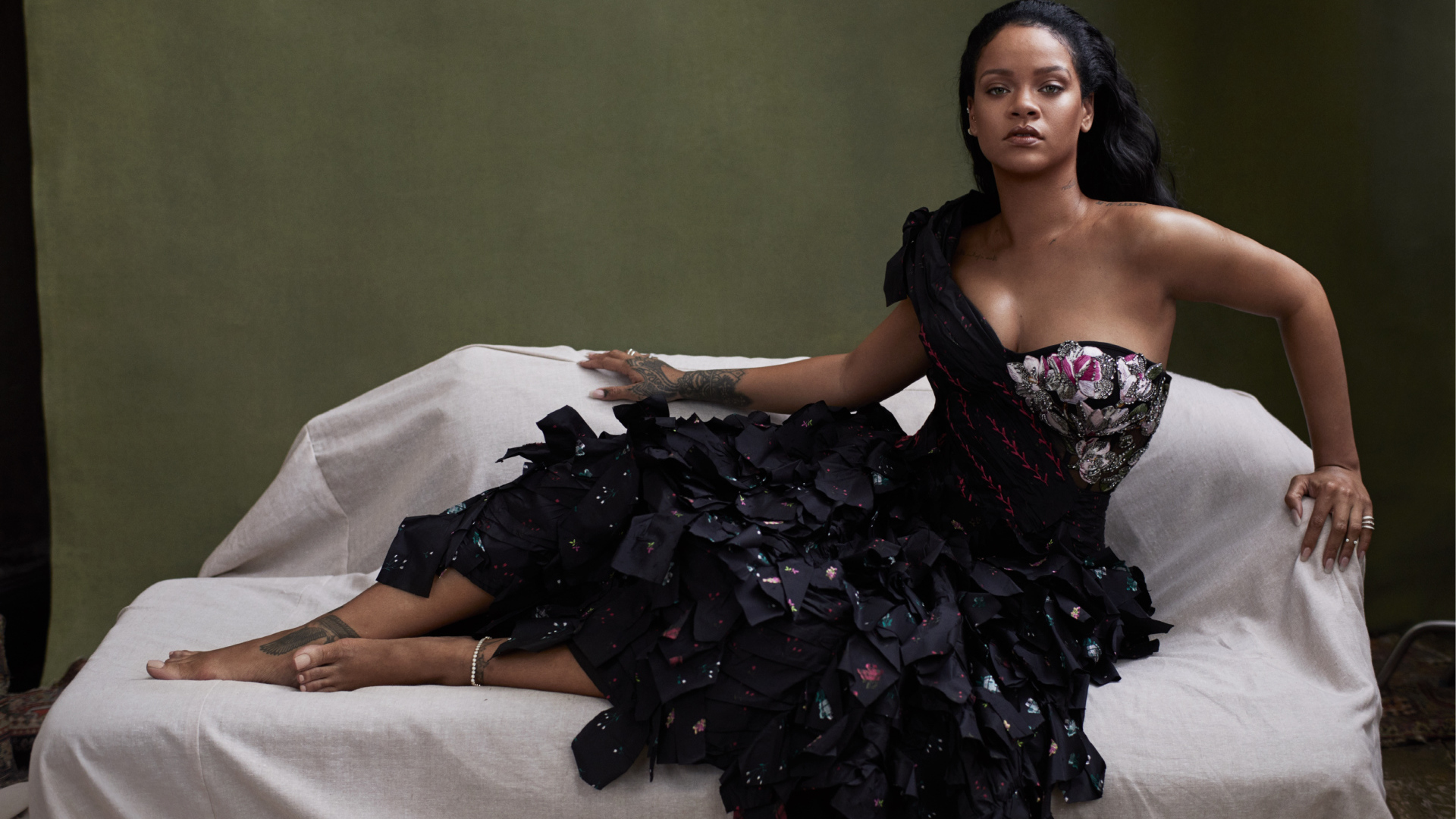 Певица Рианна в черном платье на диване 