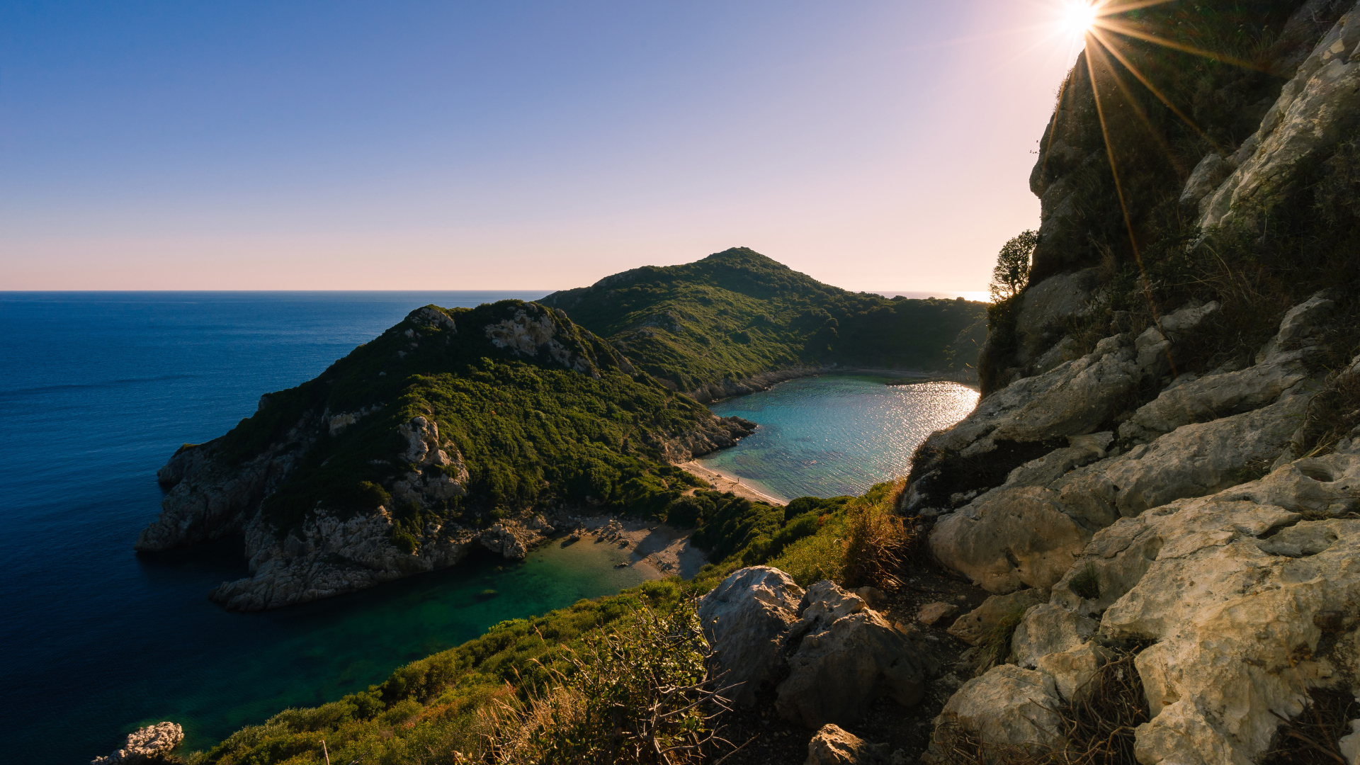 Яркое солнце за скалой у тихого моря