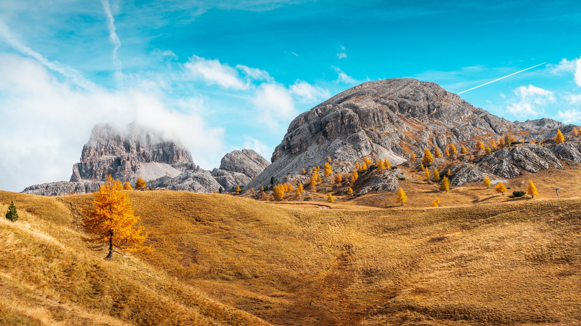 Холмы с сухой травой у гор под голубым небом