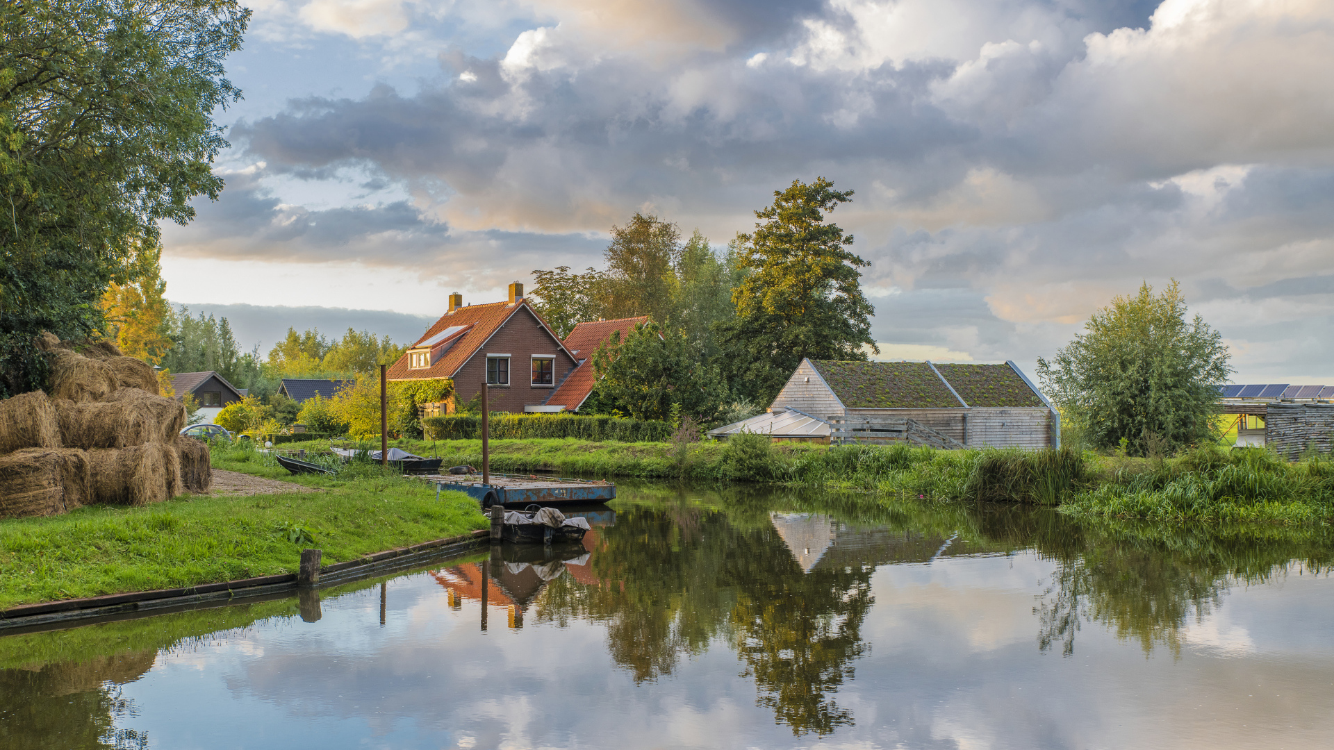 Дома отражаются в реке под небом с белыми облаками
