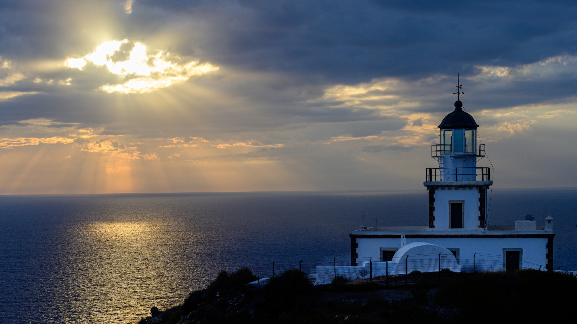 Белый маяк на берегу в лучах солнца у моря 