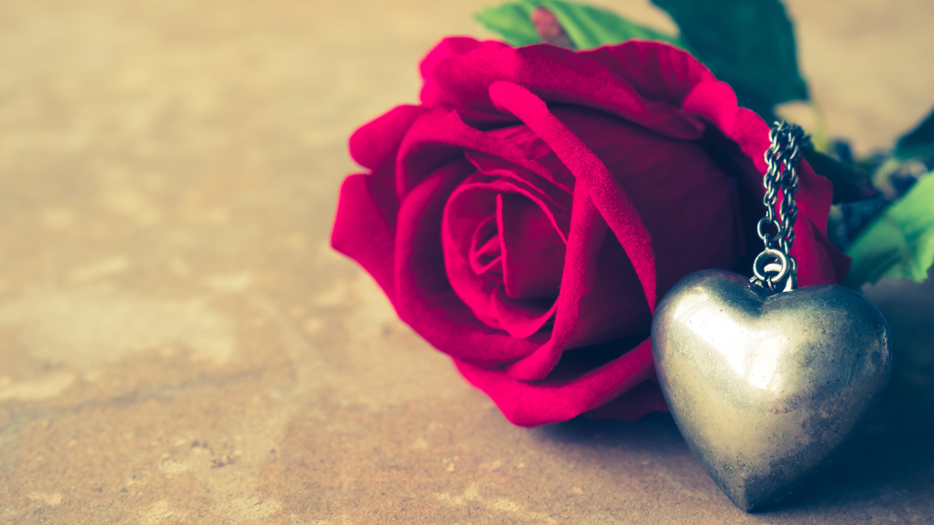 Искусственная роза с кулоном на столе