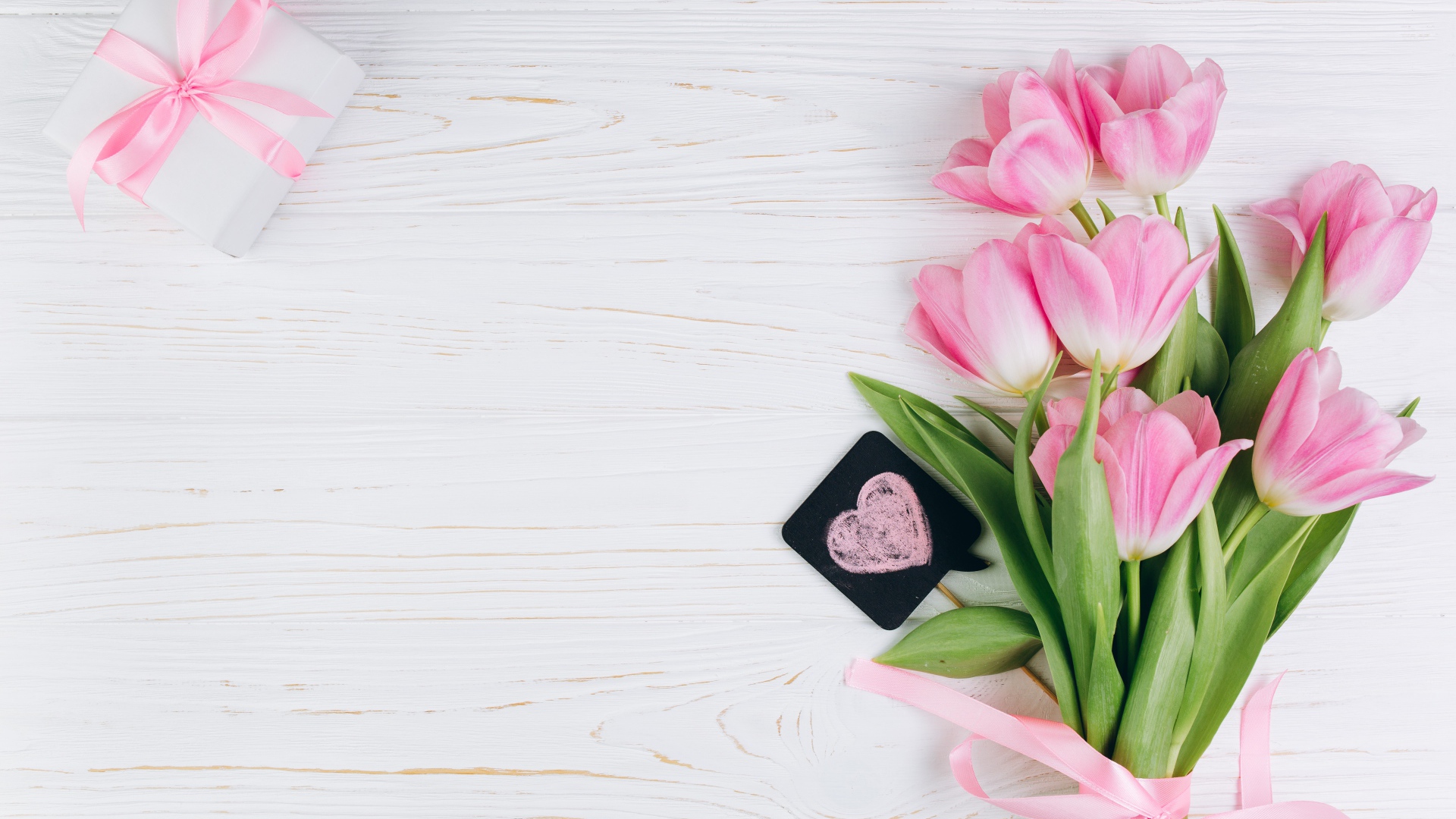 Красивый букет розовых тюльпанов с подарком на сером фоне