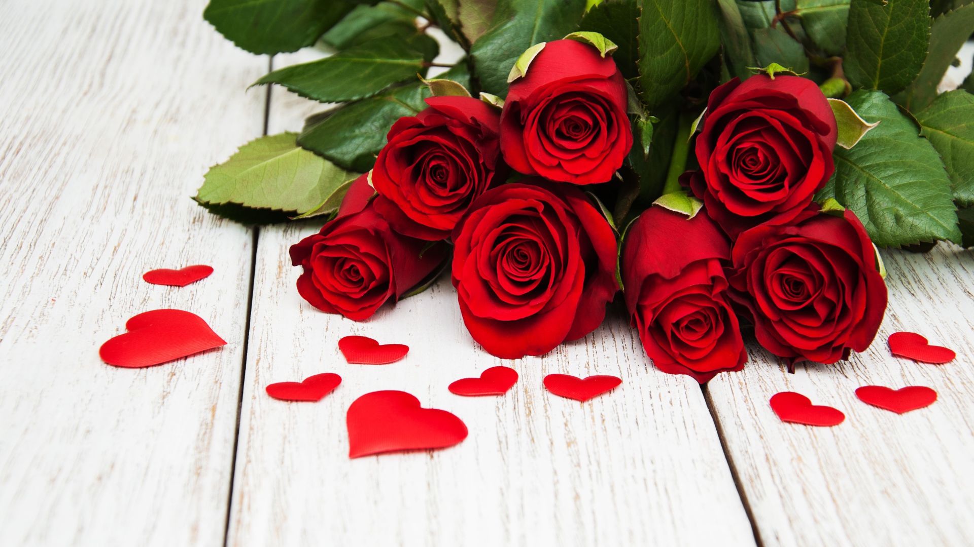 Букет красных роз с зелеными листьями на белом фоне с сердечками 