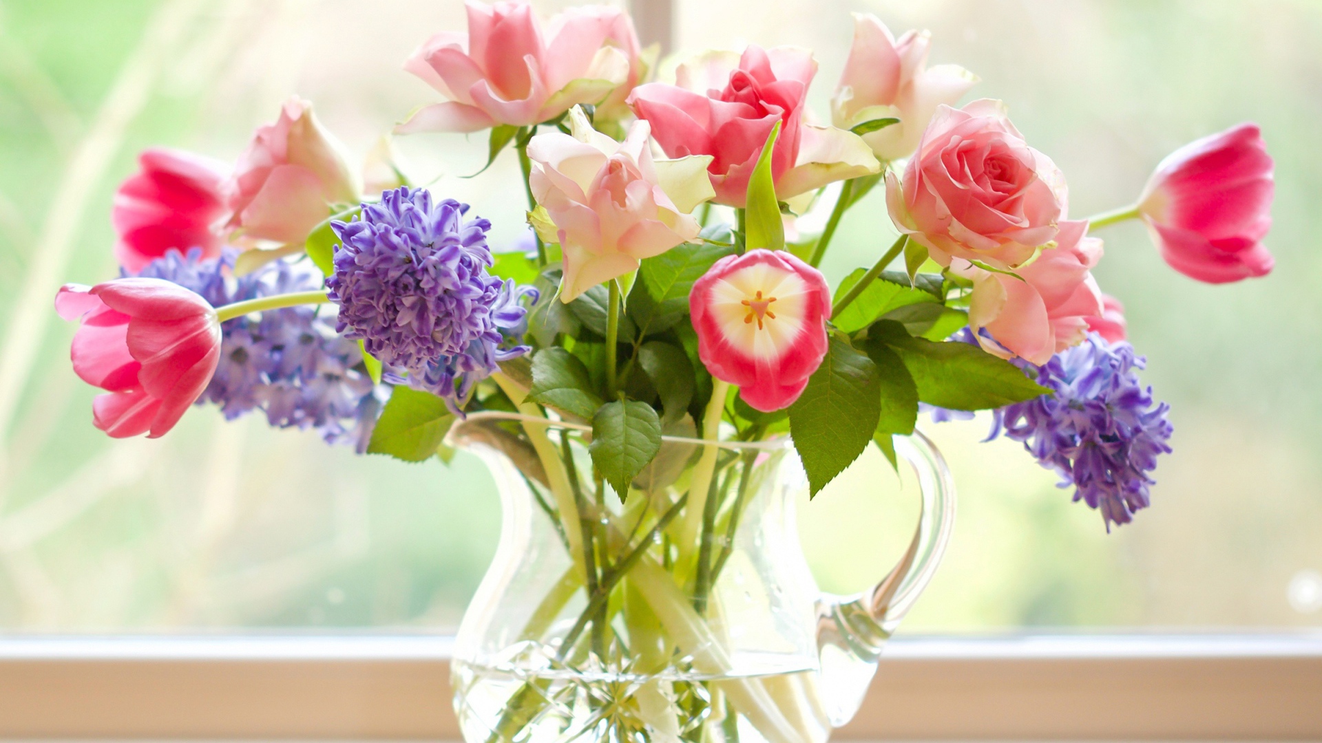 Букет роз, тюльпанов и гиацинтов в стеклянной вазе у окна